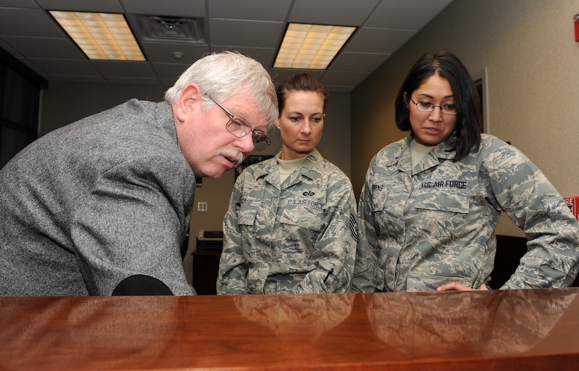 LANGLEY AIR FORCE BASE, Va. --  David Moorhouse, 1st Mission Support Group Joint-Basing office coordinator, shows Tech. Sgt. Rachel Staub, 1st Fighter Wing Command Chief's assistant, and 1st Lt. Karena Stevens, 1st Fighter Wing executive officer, how to utilize the upgraded phone system in the new 633rd Air Base Wing's building Dec. 9.  The 633d ABW will be holding its activation ceremony Jan. 7.  (U.S. Air Force photo/Senior Airman Zachary Wolf)