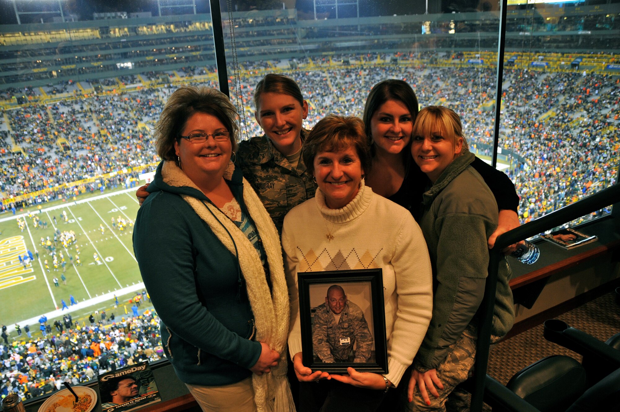 The Green Bay Packers honored military families during their recent Monday Night Football game against the Baltimore Ravens.  The Murray family was recognized at half-time on the 50-yard line at Lambeau Field and was surprised by a personal message from Lt. Col. David Murray, a nurse practitioner with the 115th Medical Group deployed to Balad Air Base, Iraq as a flight commander of the intermediate care ward at the Balad Theatre Hospital.  Theresa Murray holds a picture of her husband, David and attended the game with her four daughters (left to right) Jennifer Murray-Alston, Staff Sgt. Jamie Murray, Kelly McMeans and Staff Sgt Julie Murray who are all combat veterans, two of which are current members of the 115th FW.