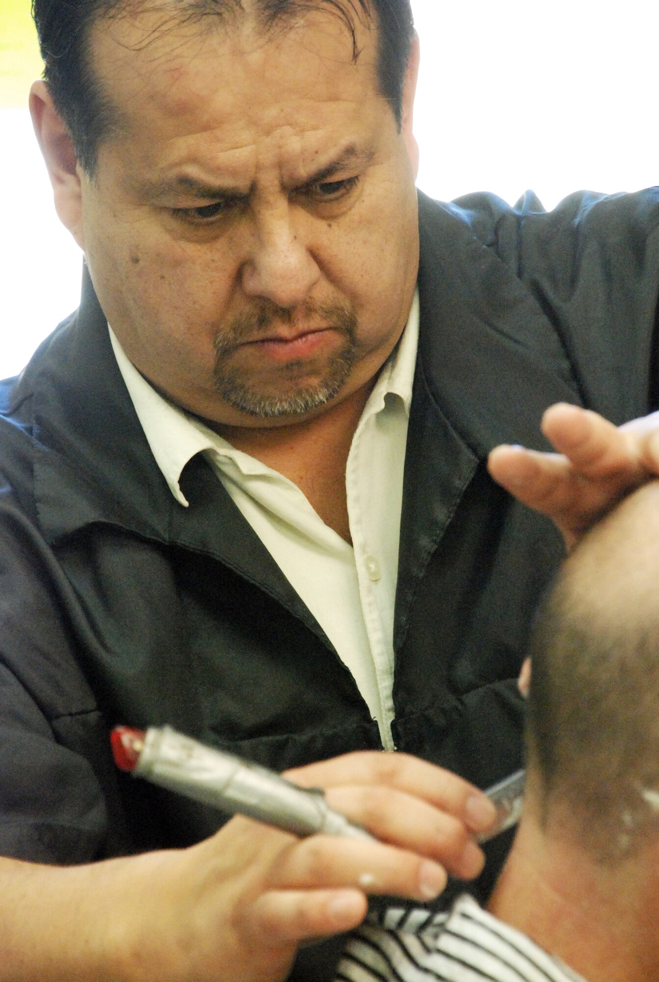 Glen Chavez, the owner of The Barber Shaak, shaves a customer’s neck Feb. 5 in the Trail’s End Club. Mr. Chavez has been cutting hair for seven years. (U.S. Air Force photo/Staff Sgt. Chad Thompson)