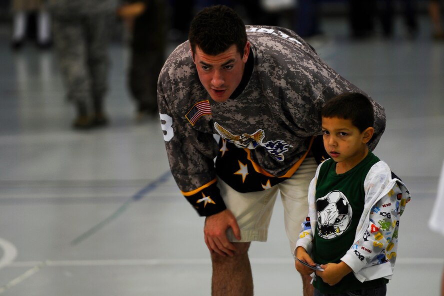 Chris Redernik from the Pensacola Ice Flyers explains how to hit a hockey puck to Aydan Jaquez, 5, during a visit to the Hurlburt Field youth center Dec. 9.  The Ice Flyers, a Southern Professional Hockey League expansion team, were also here to promote interest in the sport among those in attendance. (Air Force photo by Senior Airman Julianne Showalter)