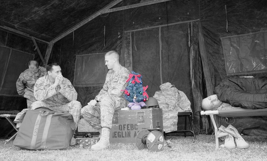 EGLIN AIR FORCE BASE, Fla. - Airmen from Team Eglin gather together to show a typical scene in deployed enviroments during the holiday season. Chief Master Sgt. Thomas Westermeyer, Command Chief, reminds people to remember our Team Eglin Warriors who are deployed during the holidays. As we enjoy this holiday season, let's remember that our family extends beyond those in our homes. Airmen united to build a tent in front of the Officers' Club and fill it with cots and other deployment items to give people perspective on the lives of the Warriors downrange. (U.S. Air Force photo illustration/Staff Sgt. Stacia Zachary)