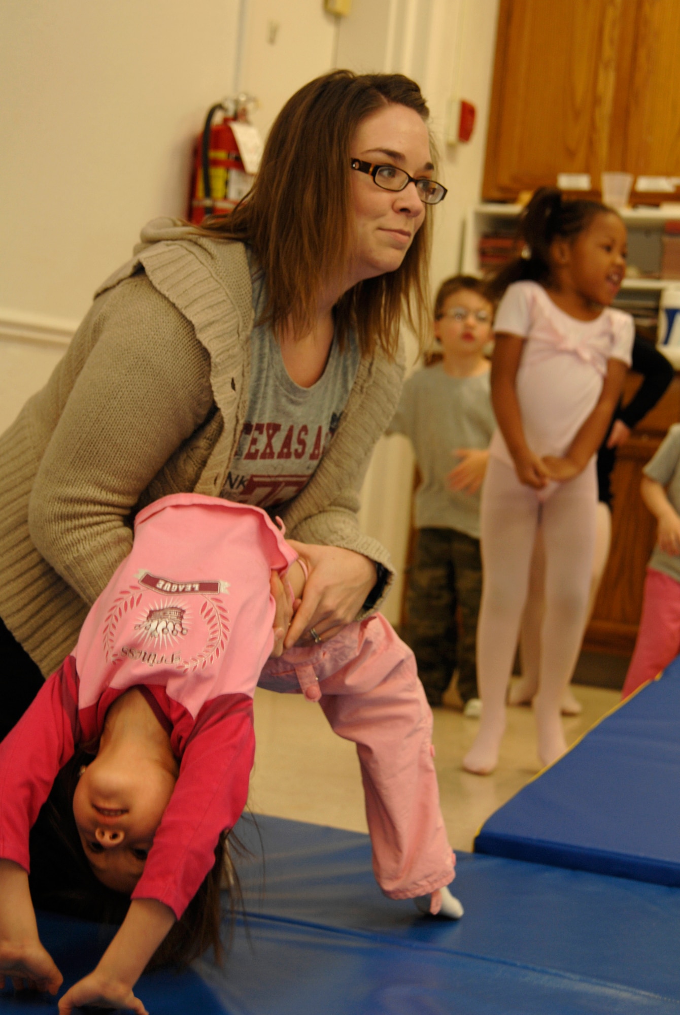 Janessa Thompson, a contracted dance instructor, helps Team McConnell children perform acrobatics in a tumble class at the McConnell Air Force Base, Kan., Youth Center, Dec. 9, 2009. Tumble class is one on several classes and activities children can attend to keep them busy during the holiday break from school. (U.S. Air Force photo/Senior Airman Jessica Lockoski)