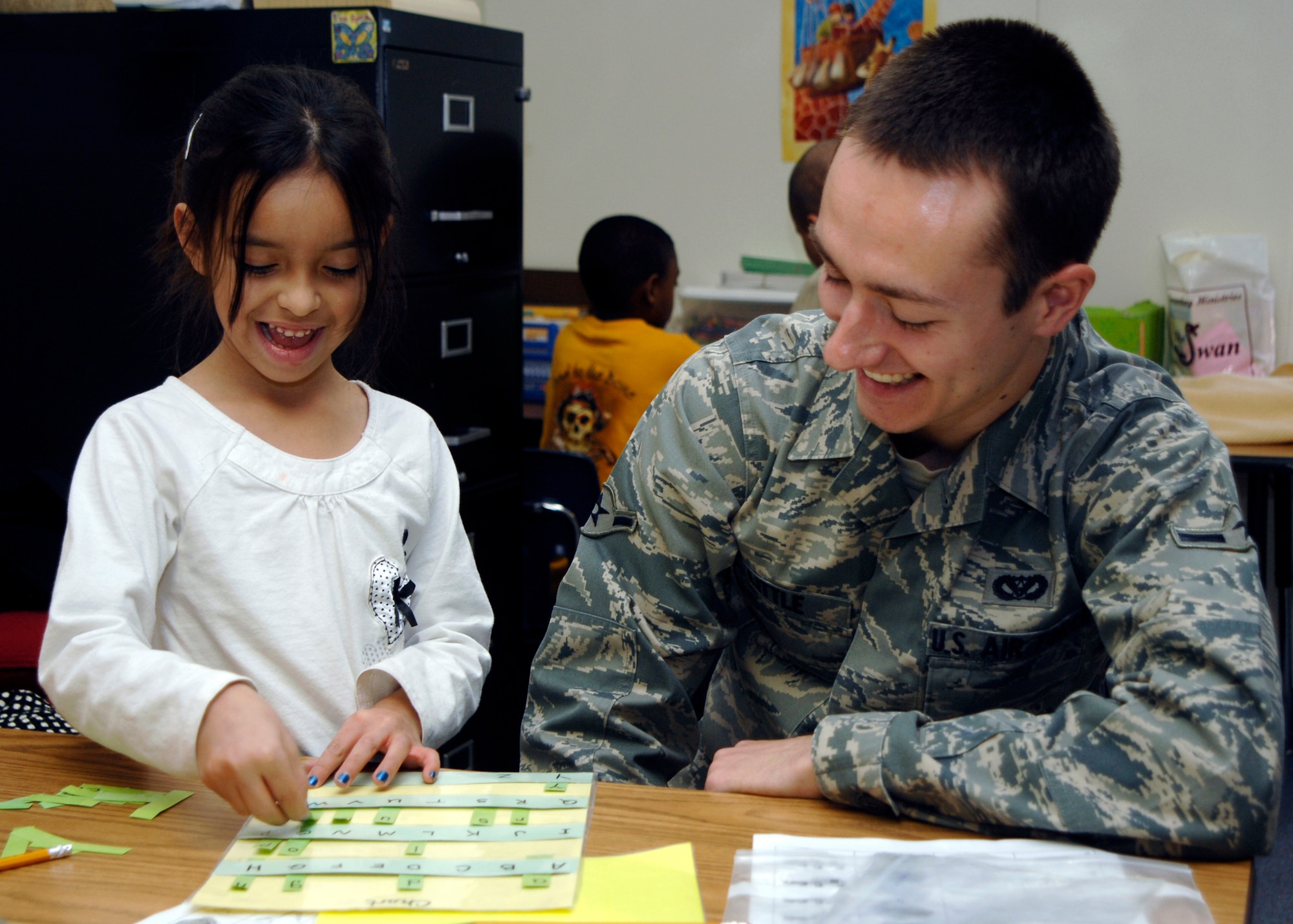CANNON AIR FORCE BASE, N.M. -- Airman Jimmy Little, 27th Special Operations Engineer Squadron, helps kindergartner Ashlynn Rivera, learn her letters Dec. 10 at Barry Elementary School through the Enrichment Program. Airman Little, a volunteer since September, said he enjoys helping  them with their academics. (U.S. Air Force photo by Airman 1st Class Jette Warnick)