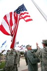 Col. William H. Mott V, 37th Training Wing commander, hoists the Lackland garrison flag for the first time Dec. 3 as members of the base honor guard keep it from touching the ground. The garrison flag is an oversized flag, 20 feet by 38 feet, which will be flown on Fridays, holidays and other special occasions. (U.S. Air Force photo/Robbin Cresswell)