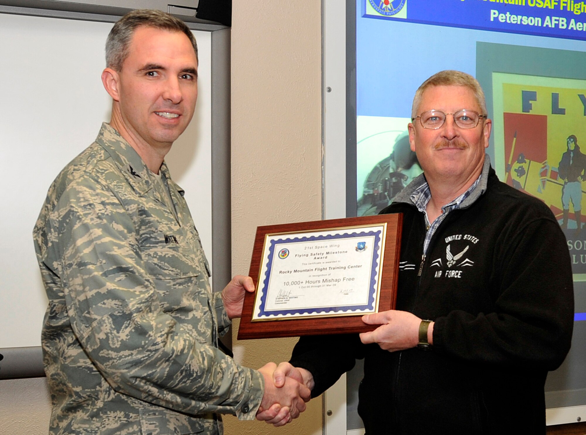 Col. Stephen N. Whiting, 21st Space Wing commander, presents Donald Cortum, Peterson aero club manager, with the 2009 Flying Safety Milestone Award Nov. 24 in recognition of the Peterson aero club’s 10,000 hours of mishap-free flying. The aero club provides low-cost flying lessons and aircraft rentals as part of the 21st Space Wing’s installation support mission. (Air Force photo)