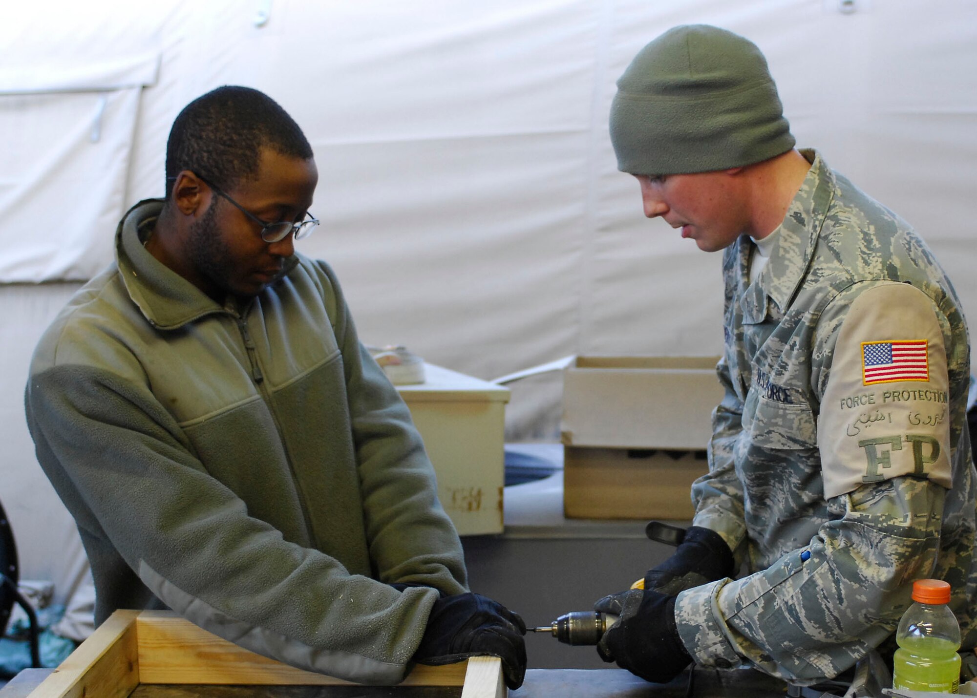 BAGRAM AIRFIELD, Afghanistan -- Airman 1st Class Michael Carey (left) and Senior Airman Matthew Roberts (right), force protection Airmen from the 455th Expeditionary Civil Engineering Squadron, work together to connect two pieces of plywood while building shelves for the laundry services office, Dec. 11, 2009.  The shelves will be use to hold laundry waiting to be picked up by the growing population of Airmen.  Airman Carey is deployed from Eglin AFB, Fla., and hails from Augusta, Ga.  Airman Roberts is deployed from Elmendorf Air Force Base, Alaska and hails from Hartford, Mich.  (U.S. Air Force photo/Senior Airman Felicia Juenke)