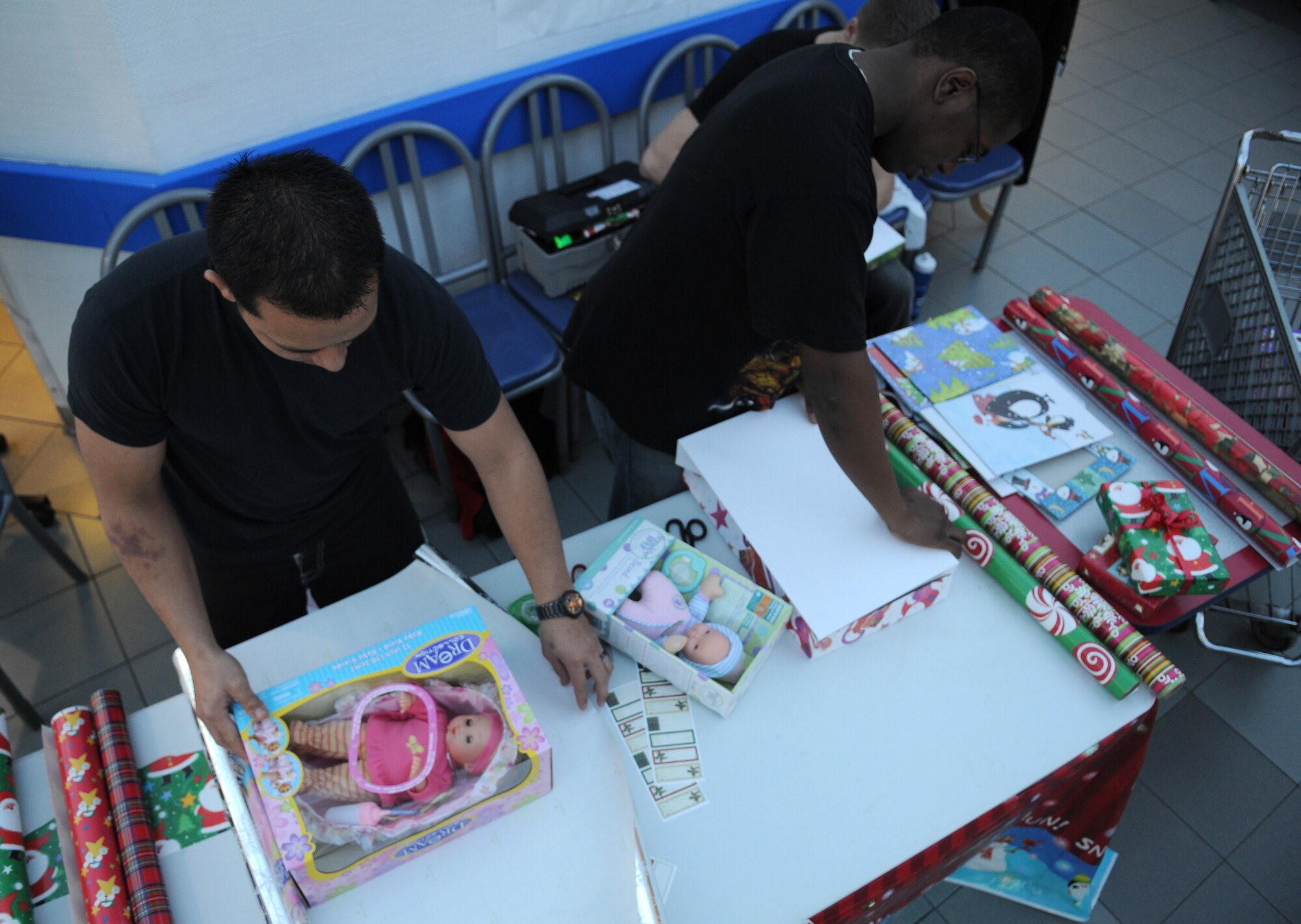 RAF MILDENHALL, England – Senior Airman Henry Matsuka and Airman 1st Class Nelson Brodhead, 100th Operation Support Squadron, aircrew flight equipment technicians, wrap Christmas gifts at the entrance of the Base Exchange Dec. 10. Donations are being accepted with all proceeds going towards the American Red Cross. (U.S. Air Force photo/ Staff Sgt. Jerry Fleshman) 