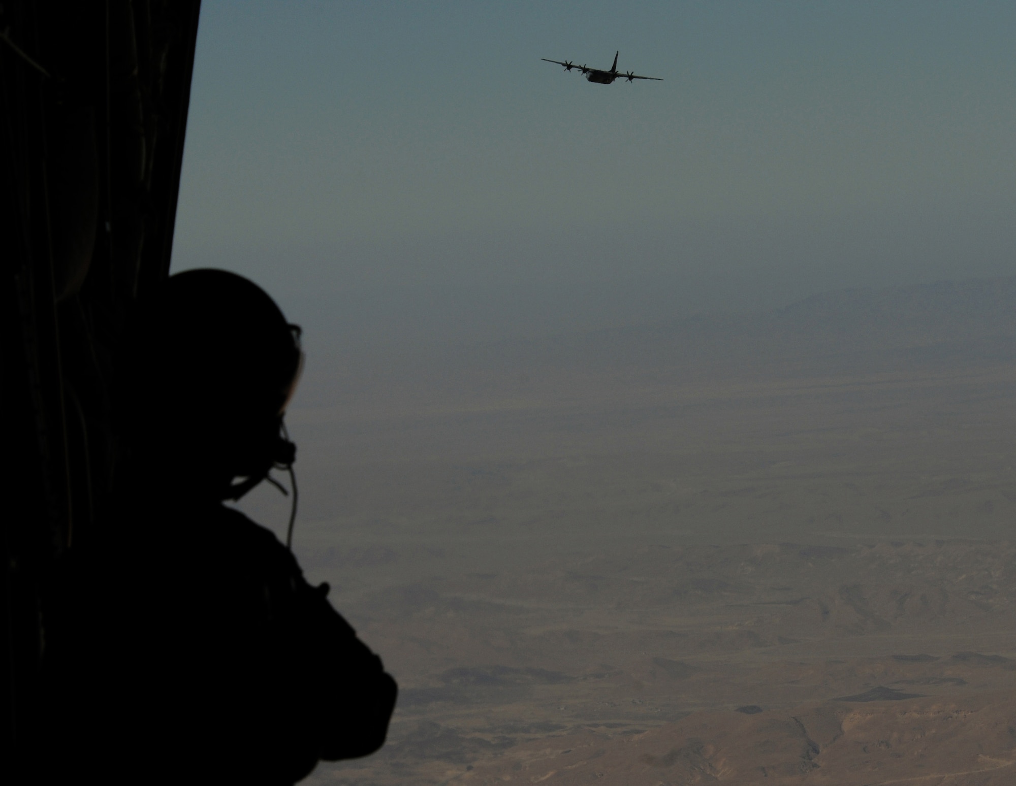 U.S. Air Force Airman 1st Class Craig Morrison, 37th Airlift Squadron loadmaster, watches as a Ramstein C-130J Super Hercules flies in formation, Dec. 6, 2009, over the Negev desert, Israel. Ramstein units participated in a 10-day training exercise to accomplish training requirements because of the strict air restrictions in Germany. (U.S. Air Force photo by Airman 1st Class Alexandria Mosness) 