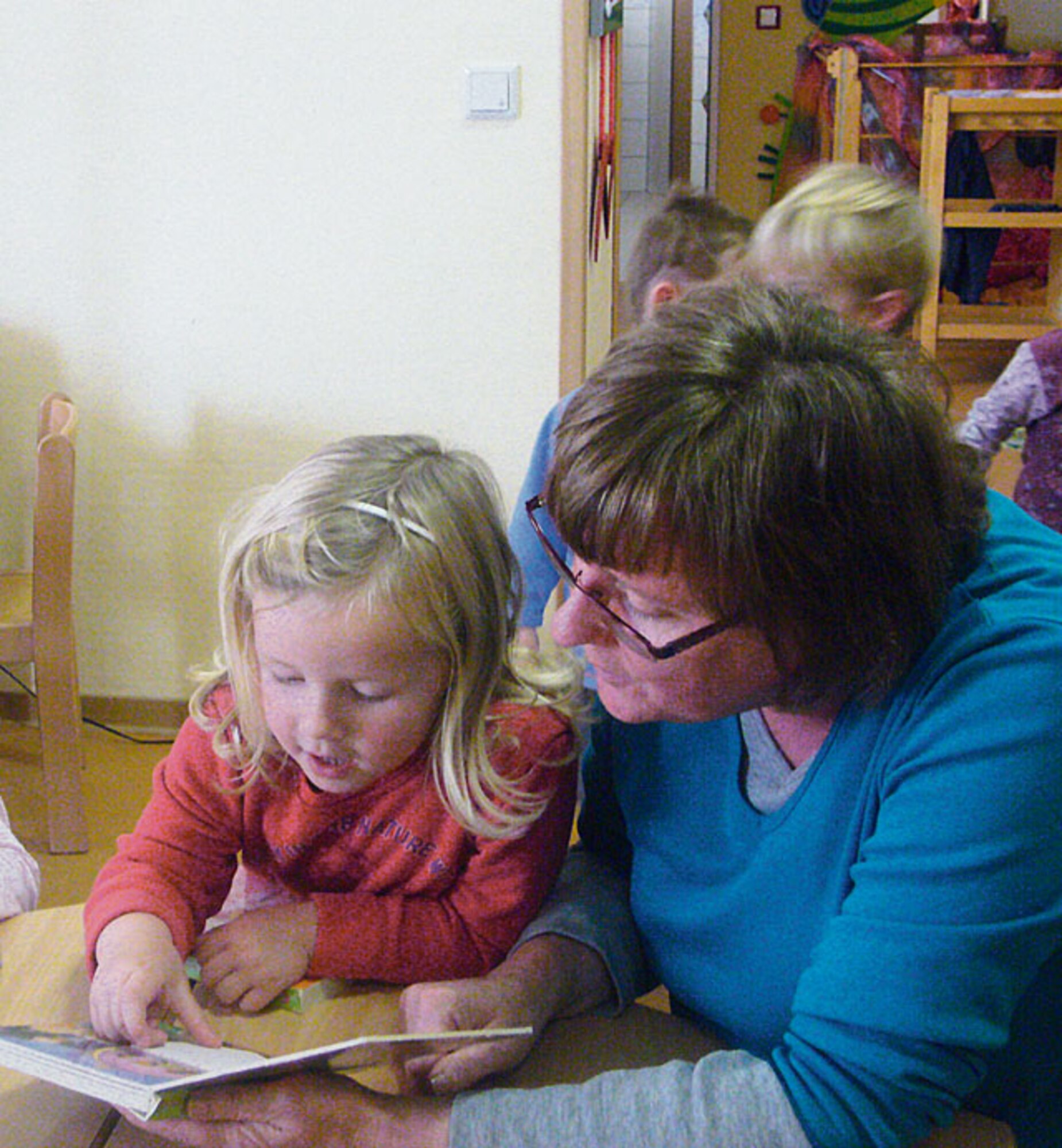 Leonie, 4, repeats the English words of items seen in a picture book, while kindergarten teacher Christine Dodd listens and corrects her. (Courtesy photo)