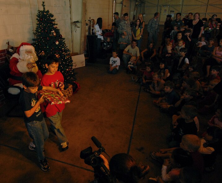 Santa Claus hands out presents to children attending a holiday homecoming party at the 33rd Rescue Squadron maintenance hangar Dec. 10. The visit by Jolly old Saint Nick topped off a week when half of the "Jolly Green Giant" unit returned from a four-month deployment to Bagram Airfield, Afghanistan.  (Air Force/Staff Sgt. Jason Lake)
