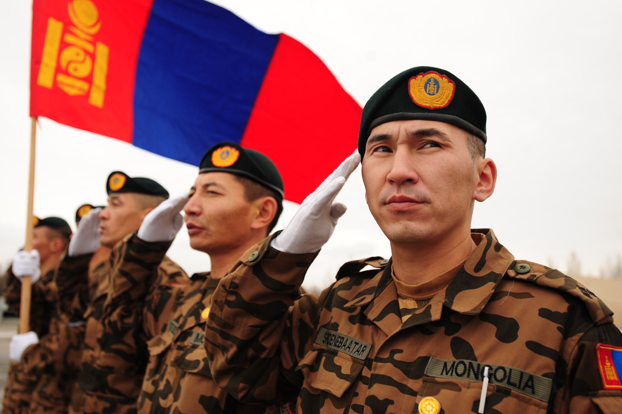 TRANSIT CENTER AT MANAS, Kyrgyzstan -- Mongolian Army soldiers salute while their nation's flag waves in the breeze at the Transit Center recently. The soldiers stayed at Manas for several days before moving forward to Afghanistan is support of Operation Enduring Freedom. (U.S. Air Force photo/Senior Airman Steele C. G. Britton)