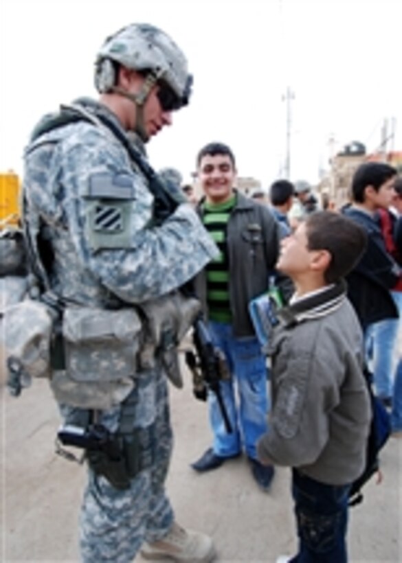 U.S. Army Staff Sgt. Cody Hoefer, assigned to Headquarters Company, 2nd Heavy Brigade Combat Team, 3rd Infantry Division, talks with children outside of the women's developmental center in the district of Quarakosh near Mosul, Iraq, on Dec. 5, 2009.  