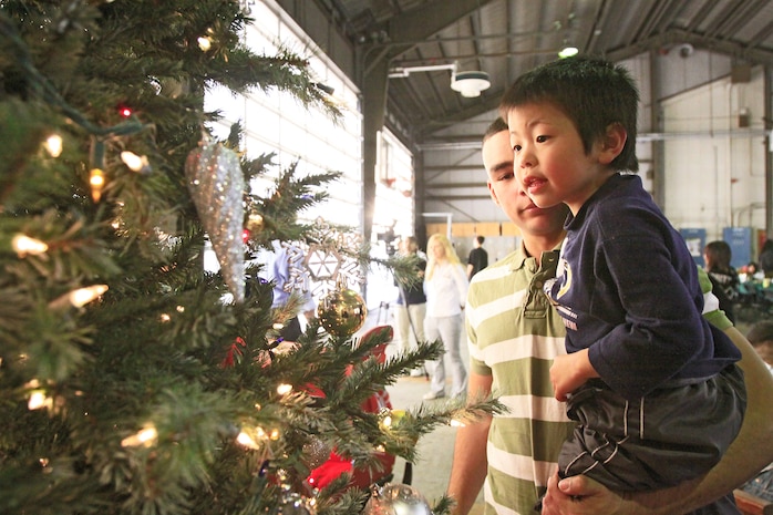 A Marine holds a young Japanese orphan from the Tsuta Orphanage up to a Christmas tree at the Aircraft Rescue Fire Fighting station here Dec. 12. ARFF Marines and family members threw a Christmas party for the orphans of Tsuta Orphanage consisting of Christmas presents, food and games.