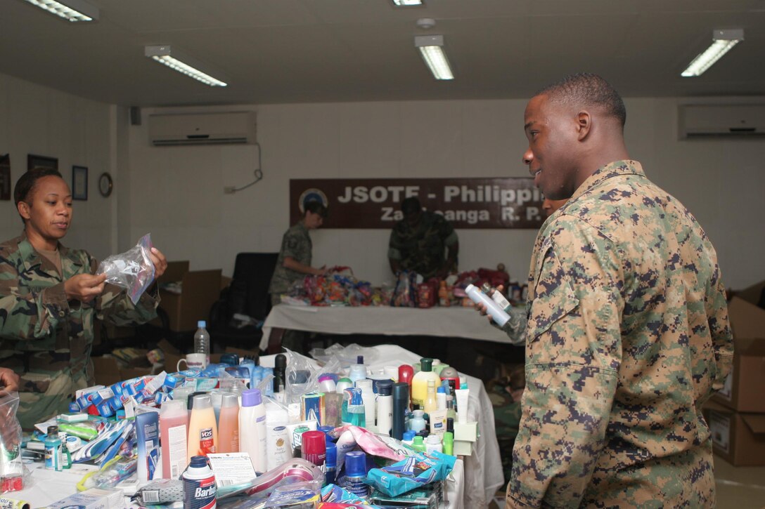 Navy Hospital Corpsman 1st Class (FMF) Lashawn Young and Marine Lance Cpl. Timothy Johnson, both assigned to Joint Special Operations Task Force-Philippines, sort through toiletries to put inside more than 600 holiday stockings. Over the next two weeks, the stockings will be delivered to all task force members. The donated items came from care packages by U.S. citizens, churches and non-profit organizations. (U.S. Marine Corps photo by Sgt. Jose Castellon/Released)