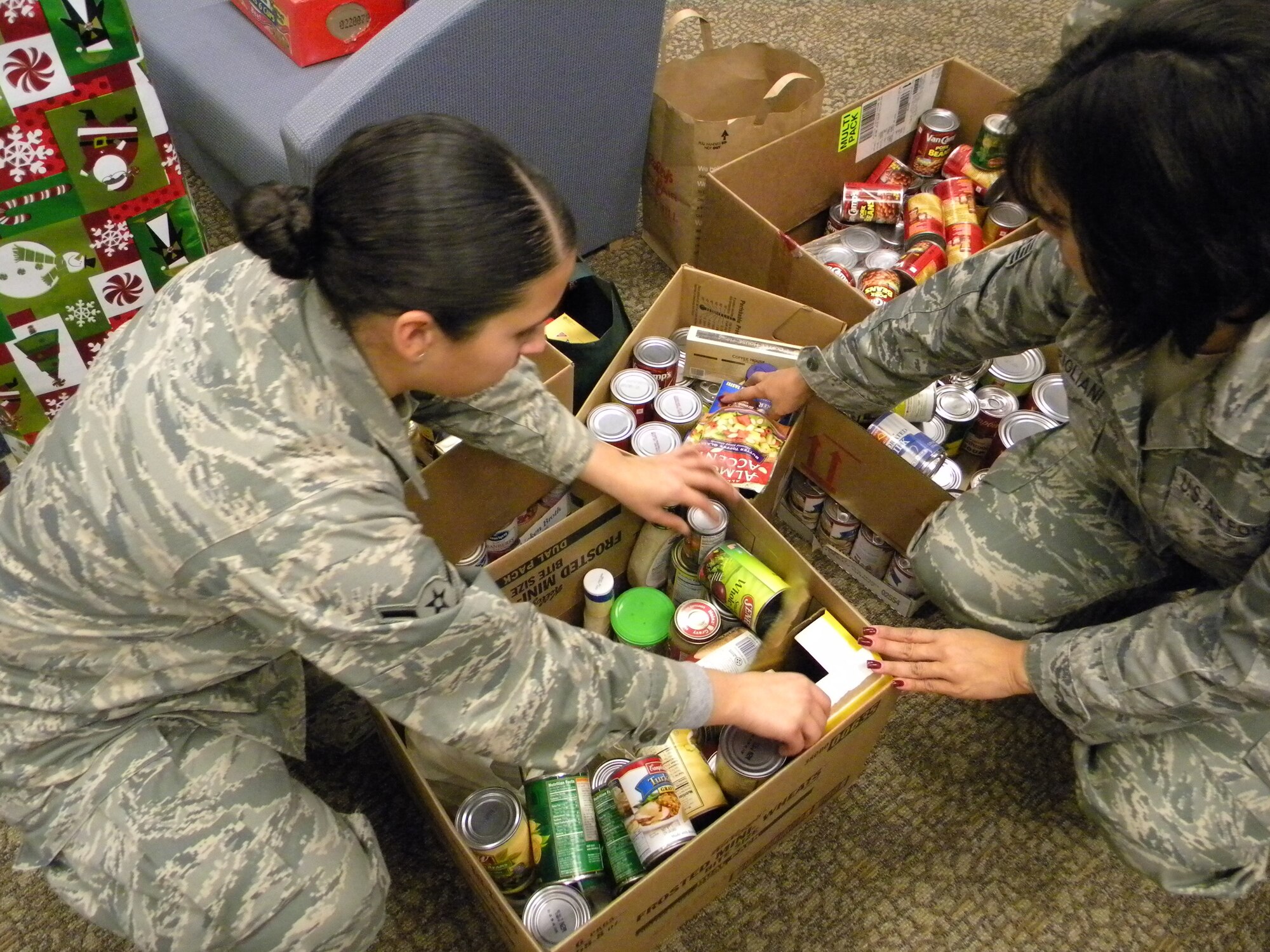 Airman Silvania Raposo and Tech. Sgt. Christine Marigliani, members of the 940th Wing Military Personnel Flight, sort through stacks of canned goods and piles of toys delivered to Airman Family Services, Dec 6,  Donations collected by units in the wing will be distributed to 940th WiG Reservists and their families, the Beale Airman's Attic, and several organizations in the communities surrounding Beale Air Force Base, Calif.  