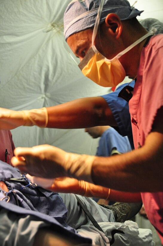 SOTO CANO AIR BASE, Honduras —  Army Dr. (Col.) David Cancelada, mobile surgical team commander, stiches up a patient's chest after a minor operation during an exercise here Dec. 10.  The team performed five minor surgeries removing "lumps and bumps" to add some realism to the exercise. The team itself is 100 percent mobile with a two-hour activation response time, and it can function alone for up to 72 hours. Their capabilities are to provide five major life- or limb-saving operations consecutively, and provide advanced trauma life support to 15 patients as well as providing limited post-operative recovery for surgical patients prior to evacuation (U.S. Air Force photo/Staff Sgt. Chad Thompson).