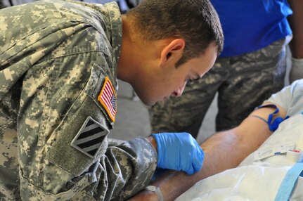 SOTO CANO AIR BASE, Honduras —  Army Sgt. Carlos Morales, a member of the mobile surgical team, inserts an IV into a patient's arm before a minor operation during an exercise here Dec. 10.  The team performed five minor surgeries removing "lumps and bumps" to add some realism to the exercise. The team itself is 100 percent mobile with a two-hour activation response time, and it can function alone for up to 72 hours. Their capabilities are to provide five major life- or limb-saving operations consecutively, and provide advanced trauma life support to 15 patients as well as providing limited post-operative recovery for surgical patients prior to evacuation (U.S. Air Force photo/Staff Sgt. Chad Thompson).