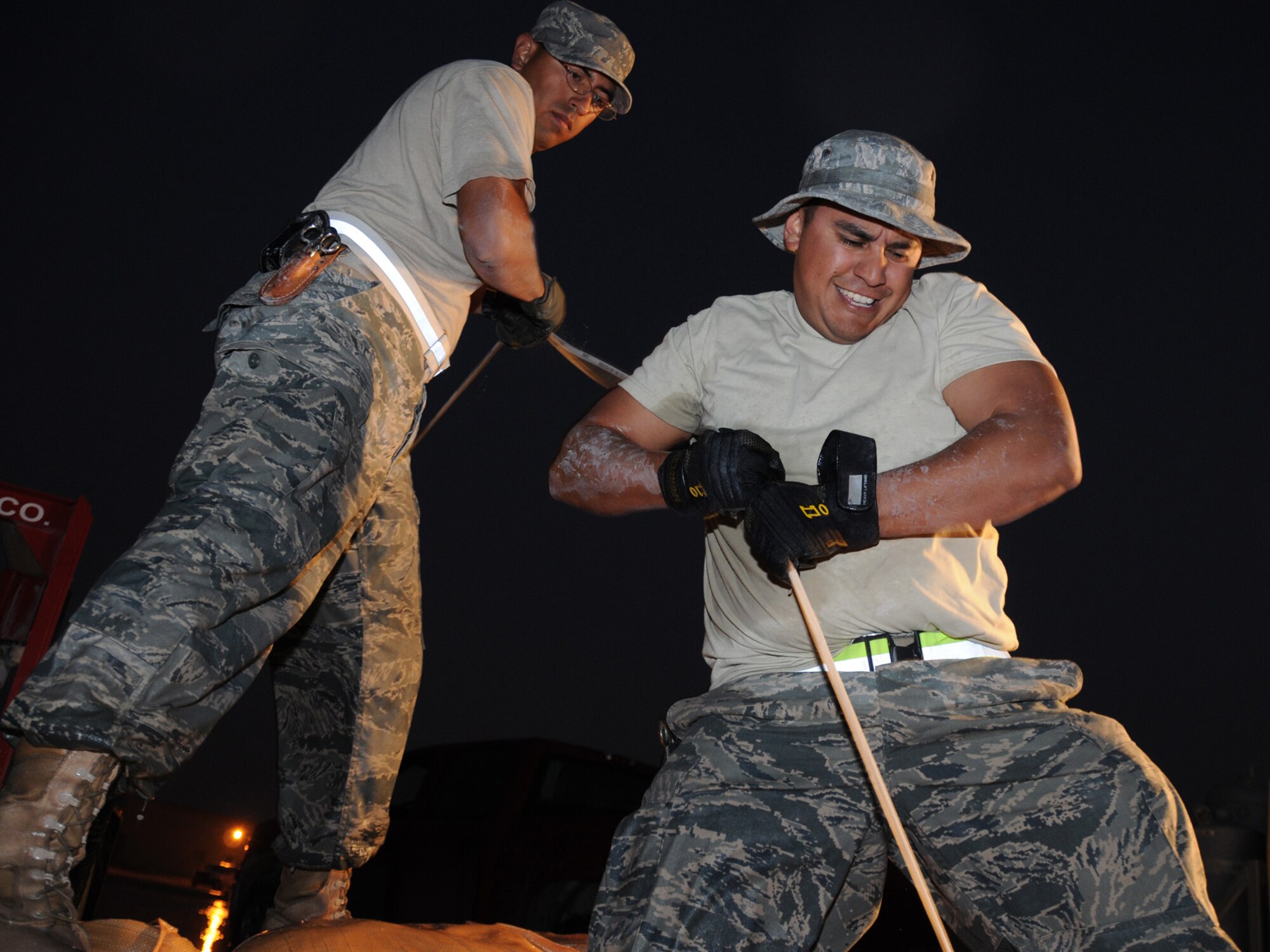 Staff Sergeants Kristofer Canales and Erik Castilleja, 379th Expeditionary Communications Squadron cable and antenna maintenance technicians, perform emergency repair on severed cables at a deployed location in Southwest Asia, Dec. 14, 2009. The base, which is located in an area that typically receives an average of 1.9 inches of rain annually, has received 1.06 inches in the last 24 hours.  (U.S. Air Force Photo/Tech. Sgt. Jason W. Edwards)