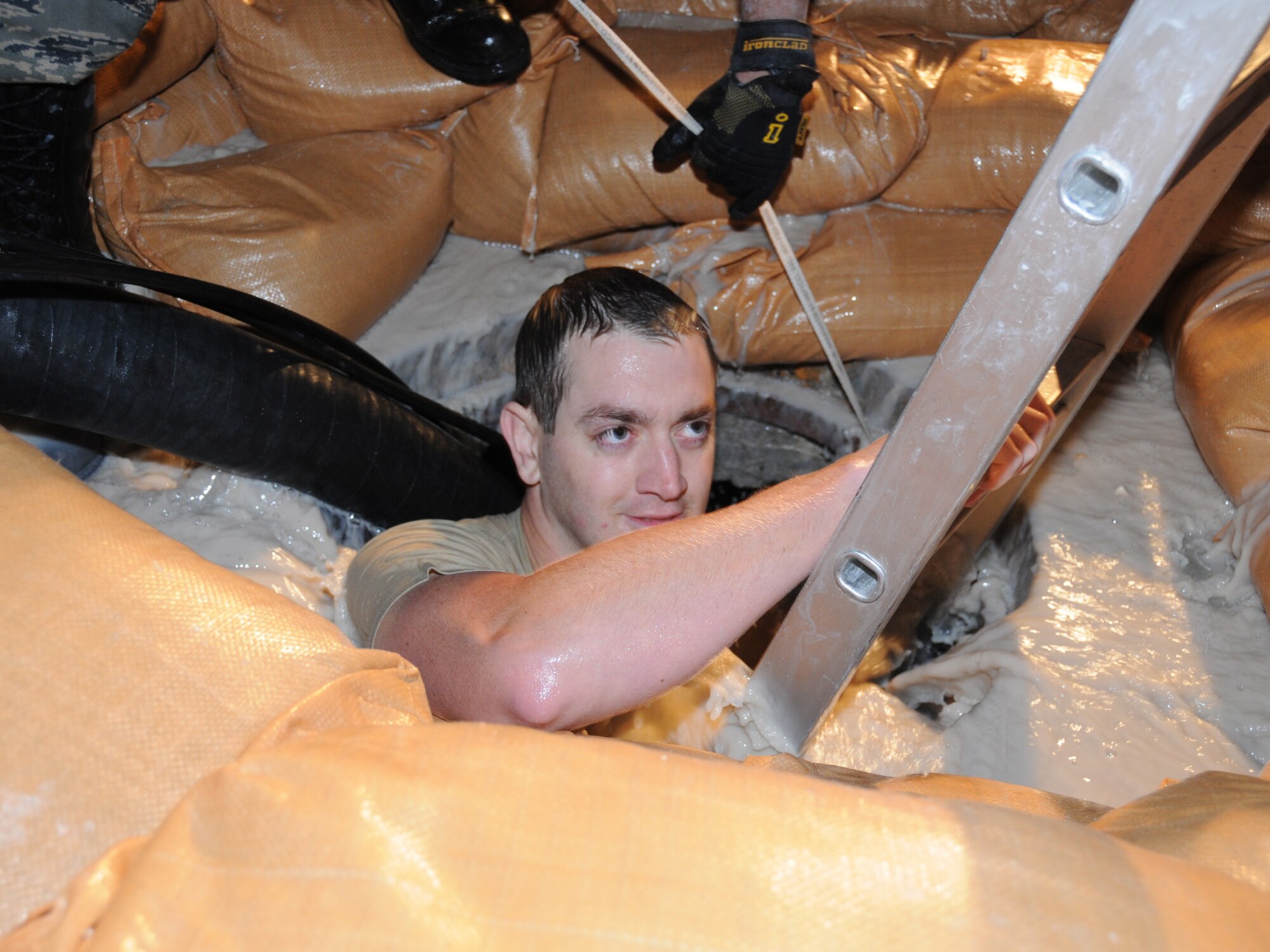 Senior Airman Bo Brauer, 379th Expeditionary Communications Squadron cable and antenna maintenance technician, descends into a flooding manhole to perform emergency repair on severed cables at a deployed location in Southwest Asia, Dec. 14, 2009. The base, which is located in an area that typically receives an average of 1.9 inches of rain annually, has received 1.06 inches in the last 24 hours. Airman Brauer is deployed from Ramstein Air Base, Germany, in support of operations Iraqi Freedom and Enduring Freedom. (U.S. Air Force Photo/Tech. Sgt. Jason W. Edwards)