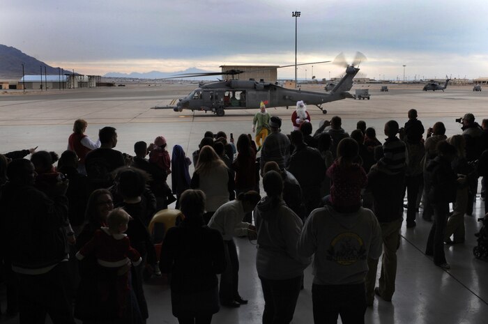 NELLIS AIR FORCE BASE, Nev.-- Airmen and their family members look on from a maintenance hanger as Santa Claus arrives in an HH-60G Pavehawk helicopter for the Nellis rescue community's annual children's Christmas party Dec. 12. The Nellis rescue community has been putting on the annual party for more than 10 years. 
(U.S. Air Force photo by Tech. Sgt. Michael R. Holzworth)
