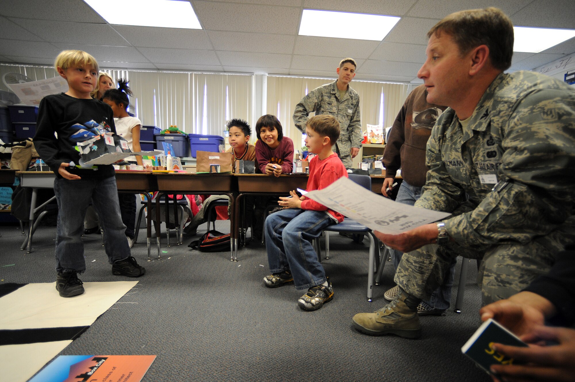 NELLIS AIR FORCE BASE, Nev.--  Tyler Bell, a third-grade student from Lomie Gray Heard Elementary School, introduces himself and presents his building proposal to Col. Steven Winklmann, 99th Air Base Wing vice commander, during the final phase of the Junior Planner Box City project Dec. 10. Colonel Winklmann spent the afternoon as acting mayor of Candy Town, helping the children at the elementary school construct and place buildings throughout their make-believe community. The architectural project helped the children understand the many different aspects that go into planning and creating a community.
(U.S. Air Force photo by Tech. Sgt. Michael R. Holzworth)
