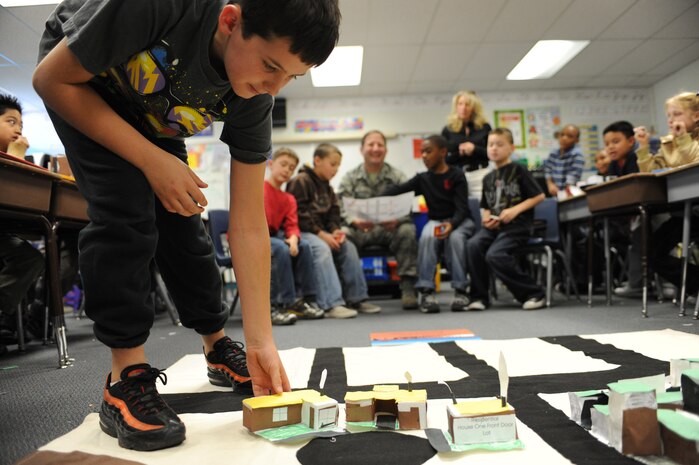 NELLIS AIR FORCE BASE, Nev.-- Ethan Hart places a mock residential building into a community while Col. Steven Winklmann, 99th Air Base Wing vice commander, and the third-grade city council at Lomie Gray Heard Elementary School vote to approve the proper zoning of residential housing during the final phase of the Junior Planner Box City project Dec. 10.  Colonel Winklmann spent the afternoon as acting mayor of Candy Town, helping the children at the elementary school construct and place buildings throughout their make-believe community.  The architectural project helped the children understand the many different aspects that go into planning and creating a community.
(U.S. Air Force photo by Tech. Sgt. Michael R. Holzworth)