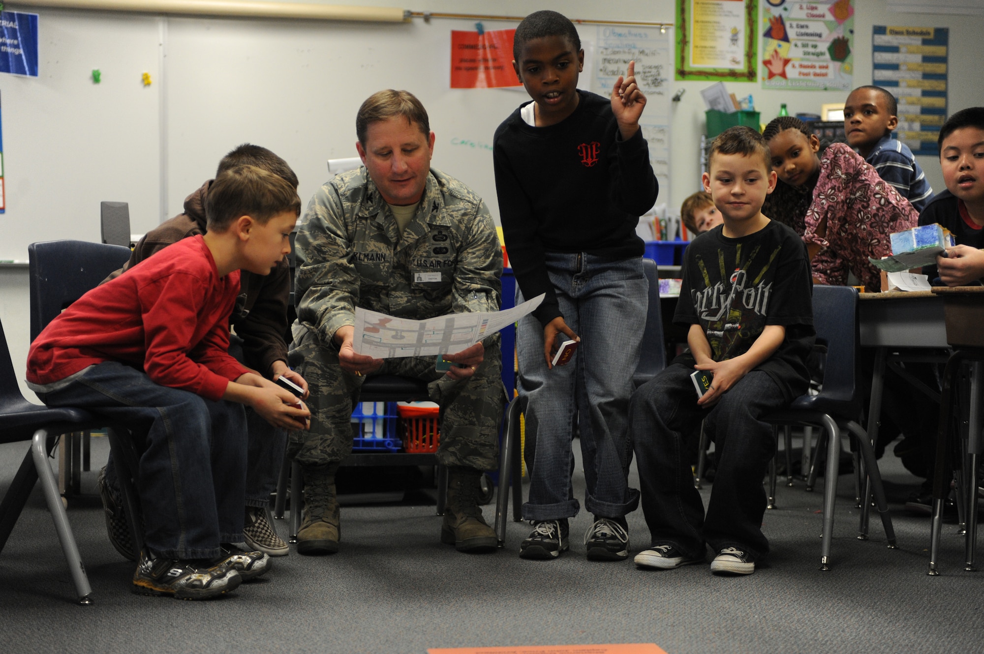 NELLIS AIR FORCE BASE, Nev.--  Col. Steven Winklmann, 99th Air Base Wing vice commander, and third grade students from Lomie Gray Heard Elementary School look over their community plans before beginning construction on their box city project Dec. 10. Colonel Winklmann spent the afternoon helping the children at the elementary school construct and place buildings throughout their make-believe community.  The architectural project helped the children understand the many different aspects that go into planning and creating a community.
(U.S. Air Force photo by Tech. Sgt. Michael R. Holzworth)