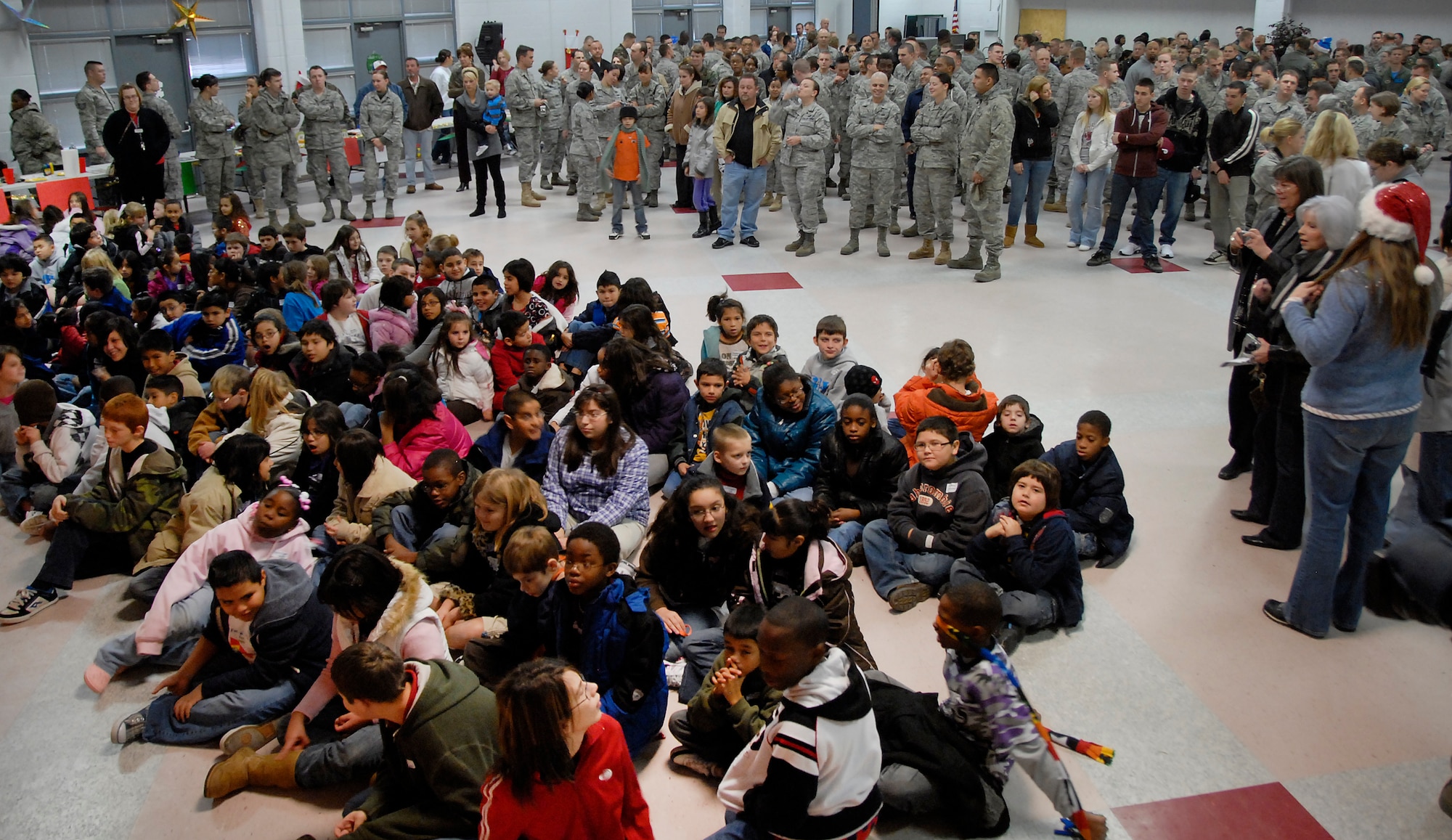 Sponsors and 200 children patiently wait for Santa Claus to arrive at the Give a Child a Christmas event Dec. 11. After Santa made his appearance, children opened presents, had a pizza lunch and participated in arts and crafts available for them. (U.S. Air Force photo/Harry Tonemah)
