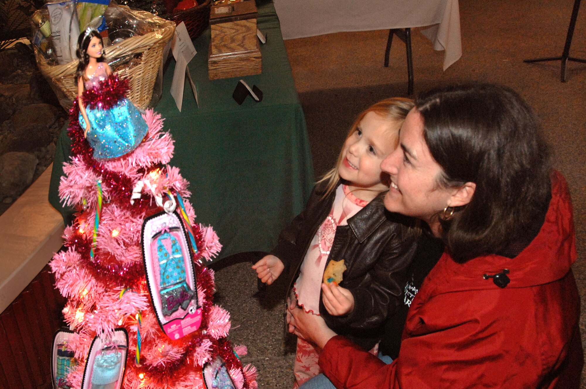 MacKenzie Hunt, left, and Laura Hunt enjoy the "pretty-in-pink" Barbie tree donated by Airman 1st Class Anjaleeqa Baldwin, Airman 1st Class Terrella Omana and Senior Airman Desiree Biggs. (U.S. Air Force photo/Nan Wylie)