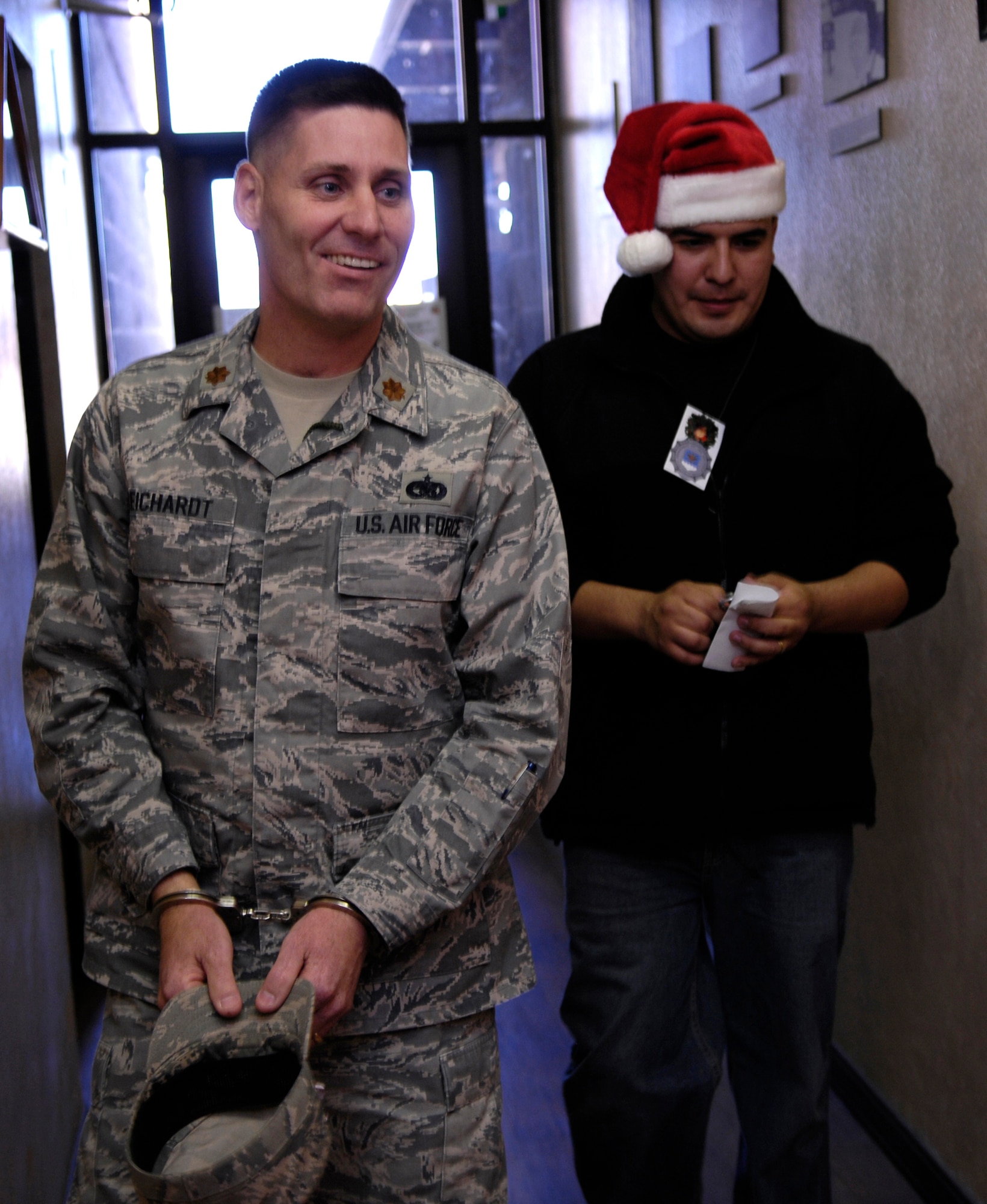 HOLLOMAN AIR FORCE BASE, N.M. -- Staff Sgt. Ismael Iniestra, 49th Security Forces Squadron and one of "santa's policemen," escorts a handcuffed Maj. Chris Reichardt, 849th Aircraft Maintenance Squadron commander, to the "North Pole Jail." Maj. Reichardt was picked up after Airmen from the 849th Aircraft Maintenance Squadron made a pledge to the security forces squadron fund raiser. The 49th SFS held the fund raiser to provide Airmen with a holiday meal. (U.S. Air Force photo by Tom Fuller)