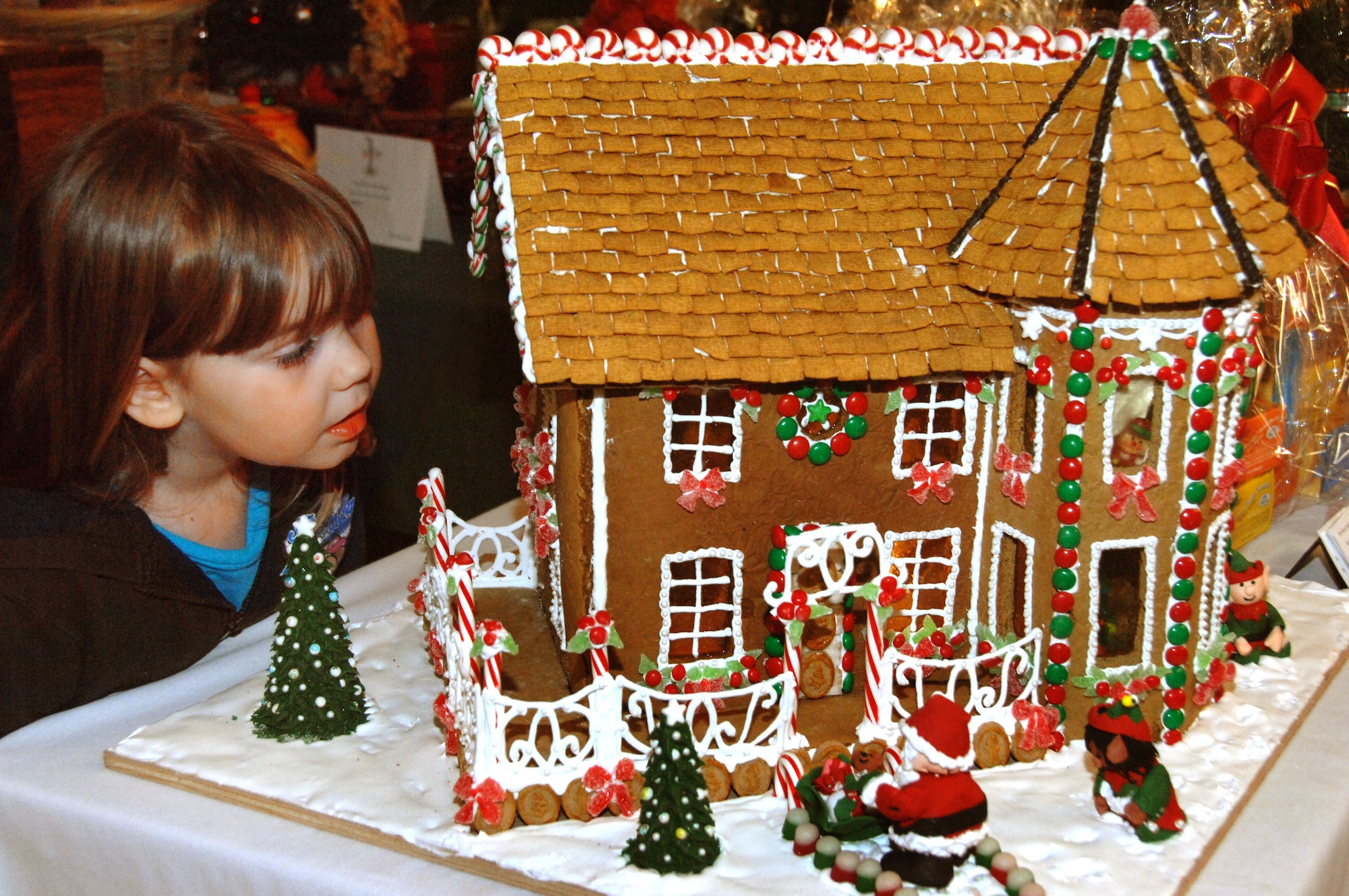 Marlo Tracy,4, checks inside a gingerbread house Dec. 4 at the Holiday Tree Festival and Auction. Lt. Col. Corey Brunson's family donated the house. (U.S. Air Force photo/Nan Wylie)
