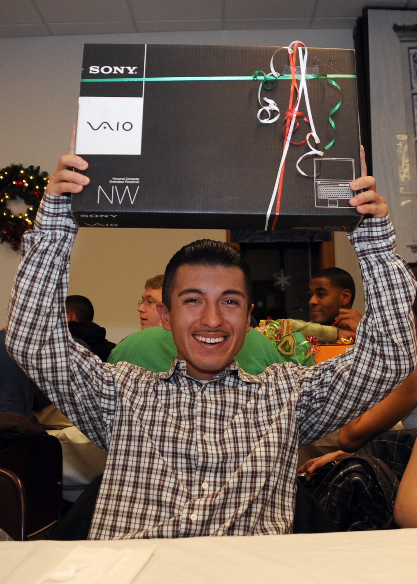 CANNON AIR FORCE BASE, N.M.-- Airman Carlos Mejia, 27th Special Operations Civil Engineer Squadron, displays the new laptop that he won at the Single Airman's Christmas Dinner Dec.10 at the base chapel. More than 30 gifts, donated by the the Clovis N.M. community, were won by lucky Airmen. (U.S. Air Force photo by Airman 1st Class Maynelinne De La Cruz)