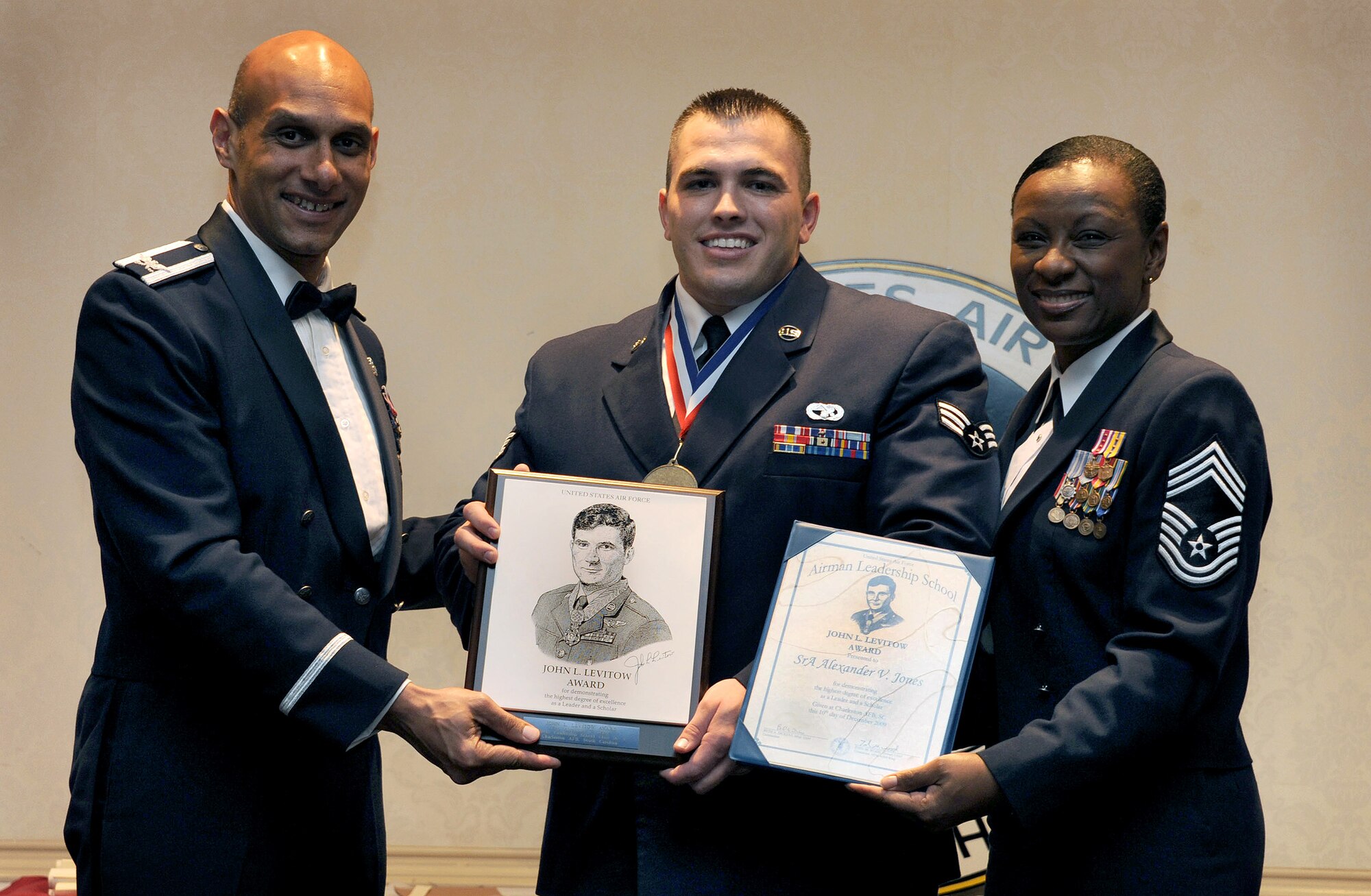 Col. Brian Robinson, left, and Chief Master Sgt. Tonia Savidge, right, present Senior Airman Alexander Jones with the John L. Levitow Award during the Airman Leadership School Class 10-A graduation the Charleston Club here Dec. 10. The award is given for a student's exemplary demonstration of excellence both as a leader and a scholar. Colonel Robinson is the 437th Airlift Wing vice commander, Chief Savidge is the 437th Medical Group superintendent and Airman Alexander is an air transportation specialist with the 437th Aerial Port Squadron. (U.S. Air Force photo/Airman 1st Class Lauren Laidlaw)