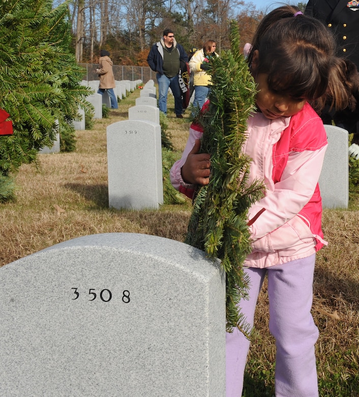 SUFFOLK, Va. -- Gianna Delavan, daughter of Staff Sgt. Reese Delavan, 1st Equipment Maintenance Squadron munitions accountability supervisor, lays a wreath on a fallen veteran's resting place, during the Wreaths Across America program Dec. 12.  Military personnel and the local community laid 2,250 wreaths on the headstones of fallen veterans.  (U.S. Air Force photo/Senior Airman Zachary Wolf)
