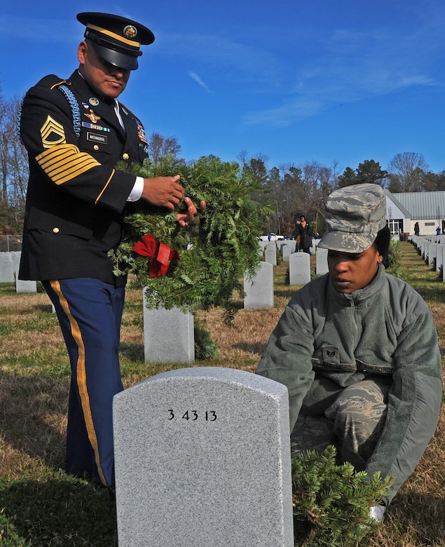 SUFFOLK, Va. -- Master Sgt. Carlos Matamoros, Joint Expeditionary Base Little Creek-Fort Story Installation Management Command garrison sergeant major, hands wreaths to Staff Sgt. Monique Barnes, 1st Logistics Readiness Squadron vehicle maintenance technician, during the Wreaths Across America program Dec. 12.  Military personnel and the local community laid 2,250 wreaths on the headstones of fallen veterans.  (U.S. Air Force photo/Senior Airman Zachary Wolf)
