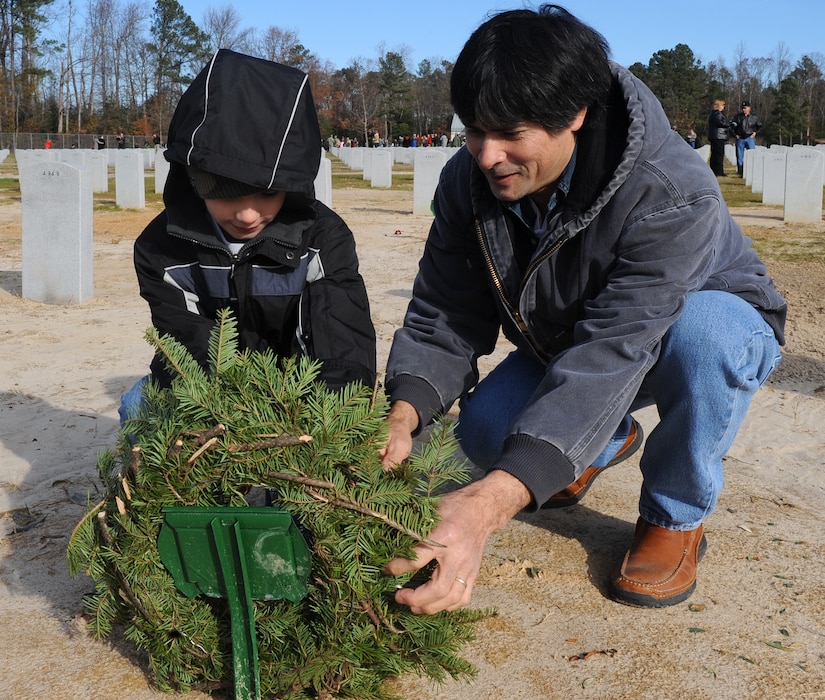SUFFOLK, Va. -- Tai Swindells and his son, Dakota Swindells, lay a wreath on the resting place of James M. Swindells, Tai's father and World War II veteran, during the Wreaths Across America program Dec. 12.  Military personnel and the local community laid 2,250 wreaths on the headstones of fallen veterans.  (U.S. Air Force photo/Senior Airman Zachary Wolf)
