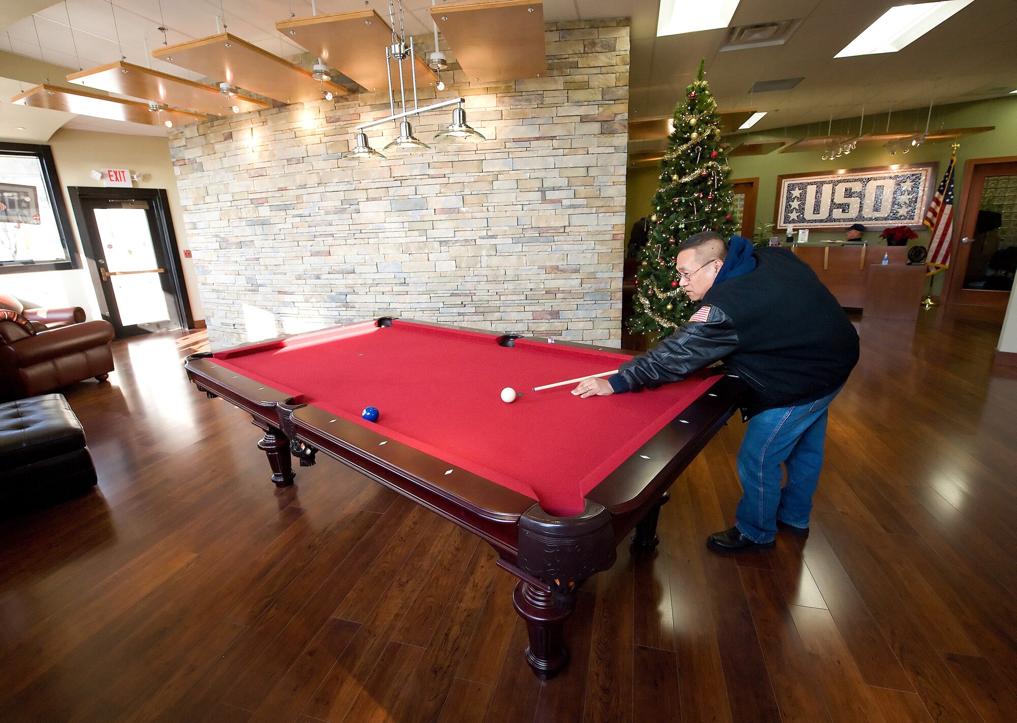Jaime Rosales, retired Army master sergeant, plays pool at the USO Lounge in the Dover Air Force Base Passenger Terminal while waiting for a space available flight. The lounge includes a computer lab and game stations with rentable videogames. (U.S. Air Force photo/Jason Minto)