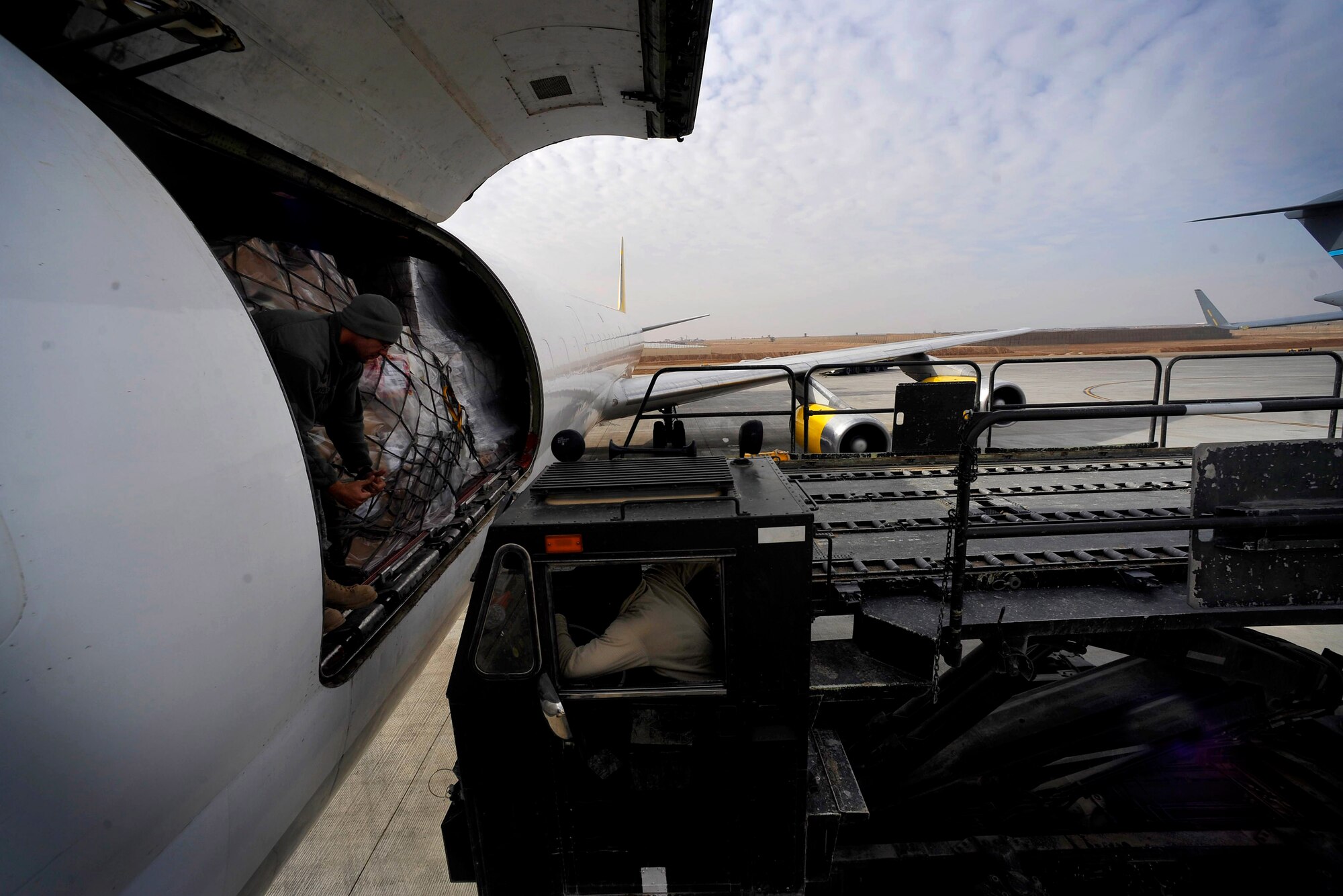 U.S Air Force Staff Sgt. Nick Pinette, 451st Expeditionary Logistics Readiness Squadron Det. 1 air transportation specialist, stationed at Pope AFB, N.C., deployed to Camp Bastion, Afghanistan, helps direct a 60K loader to a DHL DC8 aircraft, Dec. 11, 2009. The members from the 451st ELRS received 18 pallets of mail and supplies for the members of Camp Bastion. (U.S. Air Force photo/Staff Sgt. Angelita Lawrence)