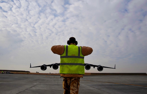 A British Air Force member guides a U.S Air Force C-17 Globemaster III that landed at Camp Bastion, Afghanistan, into its parking spot, Dec. 11, 2009. The C-17 is delivering MRAPs to provide safety and security during convoy operations. (U.S. Air Force photo/Staff Sgt. Angelita Lawrence)