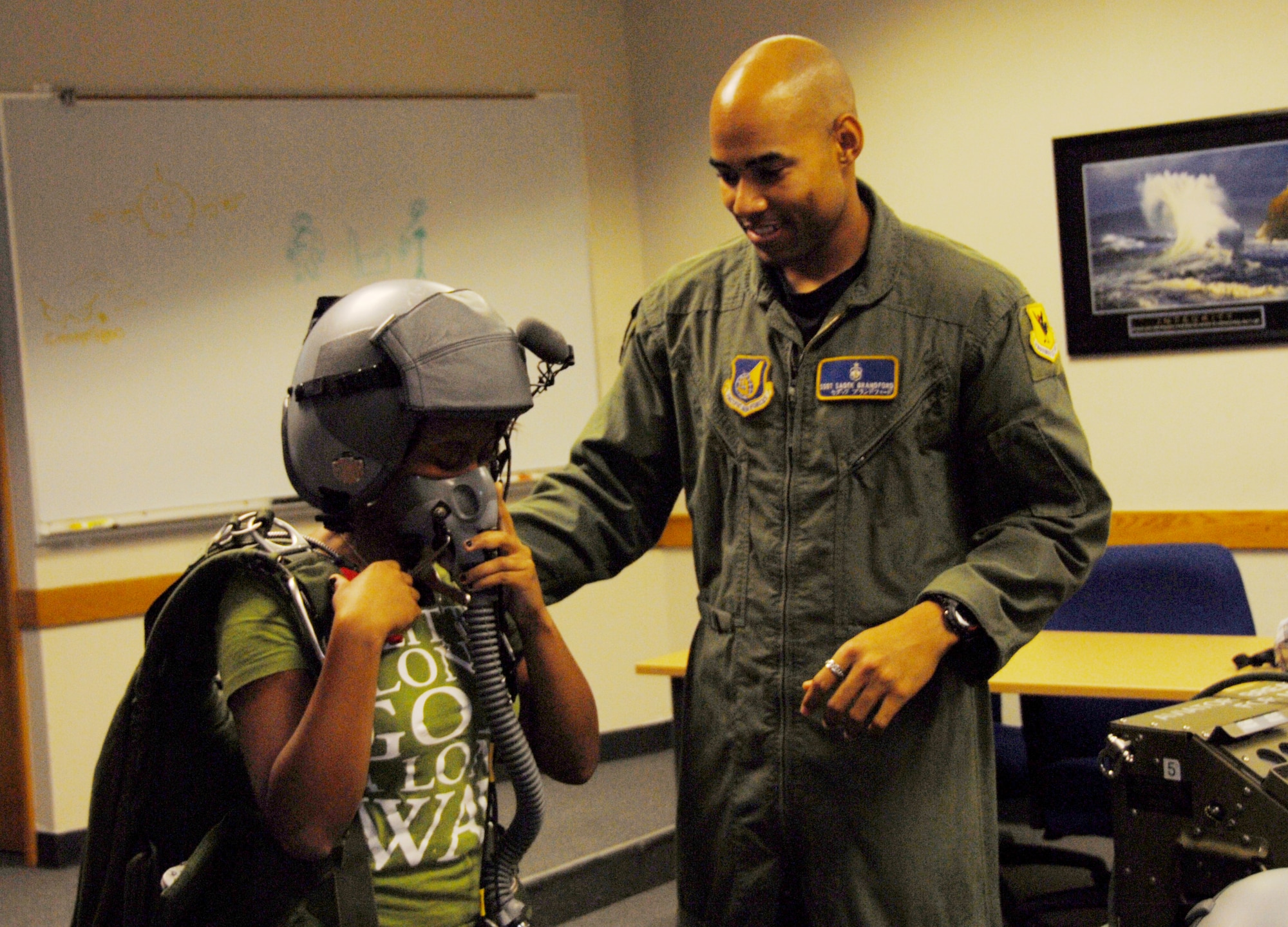Staff Sgt. Sadek Brandford, 18th Medicine Squadron Physiological Training Flight, helps a student from the Kadena High School physics class into a life-support suit during a “Physics in Flight” themed fieldtrip Dec. 11. The students learned how physics relates to aviation and witnessed how those theories are applied at Kadena. Students received briefings and tours of the 67th Fighter Squadron including the flight line, 18th Aerospace Medical Squadron Physiological Training Flight and 18th Operations Support Squadron Radar Approach Control. (U.S. Air Force photo/Staff Sgt. Kenya Shiloh)