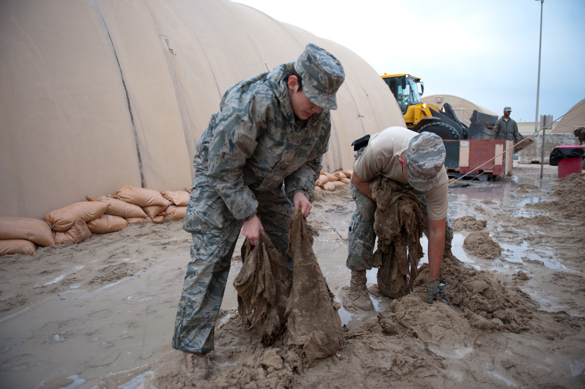 Left, Senior Airman Kelli Miller, 379th Expeditionary Communications Squadron, and Joshua Smith, 379th Expeditionary Civil Engineer Squadron, remove old sandbags after placing new ones, Dec. 11, 2009, in Southwest Asia. Airmen Miller and Smith are among the volunteers filling and replacing sandbags in preparation for potential flooding to common living areas here. (U.S. Air Force photo/Staff Sgt. Robert Barney) 