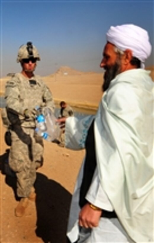 U.S. Army Pfc. Steve Masokawski, with Charlie Company, 1st Battalion, 17th Infantry Regiment, gives an Afghan man a bottle of water at a combat outpost in Rajankala, Kandahar province, Afghanistan, on Nov. 26, 2009.  The Army operates from combat outposts to add flexibility to operations in their sectors.  
