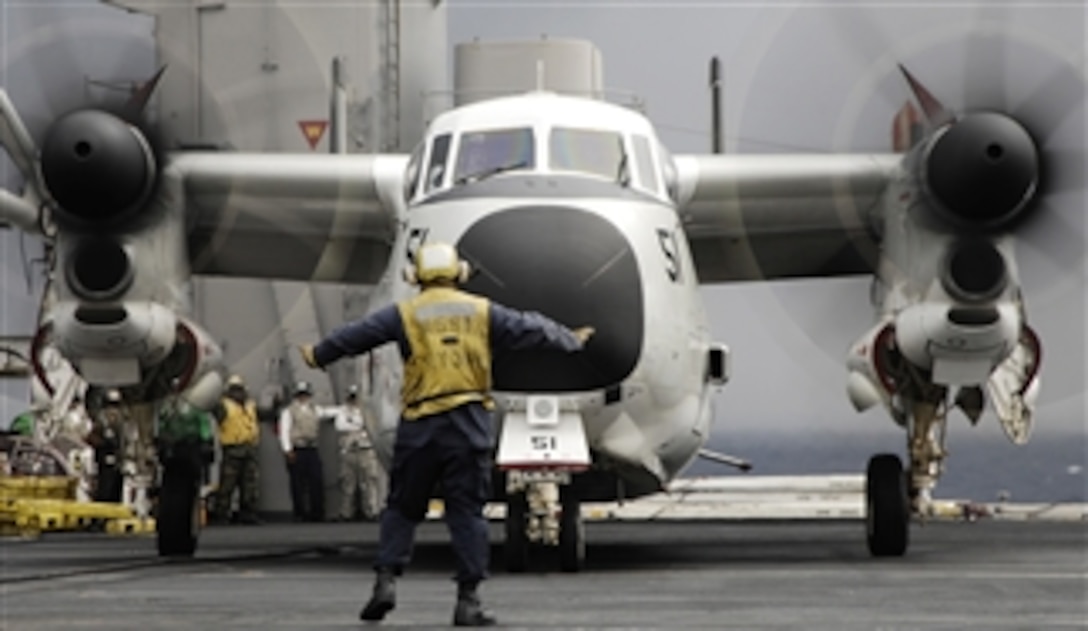 An aircraft director guides a C-2A Greyhound aircraft across the flight deck aboard the aircraft carrier USS Harry S. Truman (CVN 75) upon completion of daily flight operations while underway in the Atlantic Ocean conducting carrier qualifications on Dec. 8, 2009.  