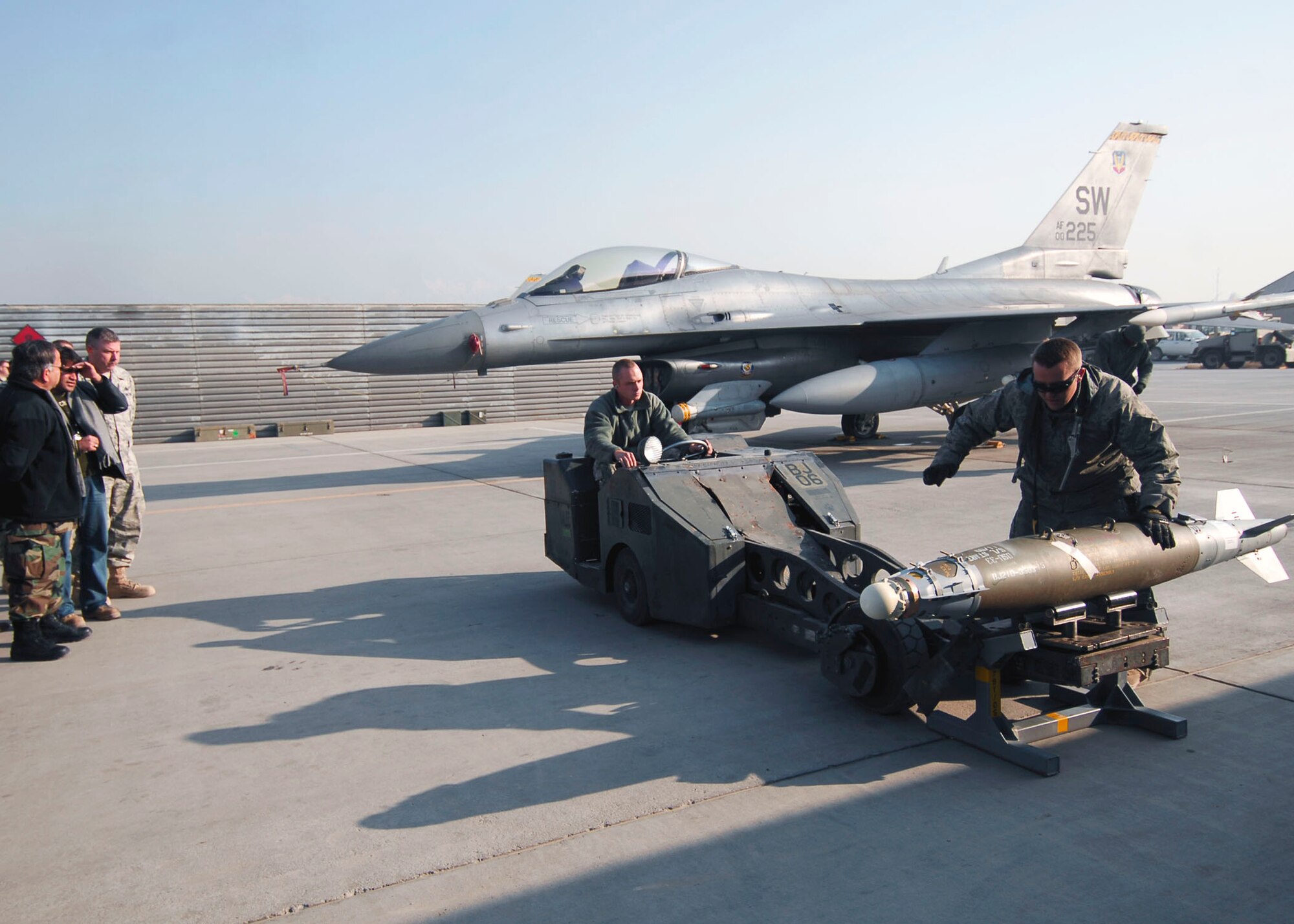 BAGRAM AIRFIELD - Staff Sgt. Sam Arpy, Weapons Load Crew leader and Des Moines, Iowa native, prepares to lift a Joint Direct Attack Munition with a “Bomb-lift Truck” while Airman 1st Class John Ackerman, a Springfield, Ill. native, prepares to tie down the bomb to the lift.  Both Airmen are deployed from Shaw Air Force Base, S.C. and were demonstrating proper loading procedures for Afghan National Army Air Corps Brig. Gen. Abdul Wahab Wardak and other officials, Dec. 19, 2009.  (U.S. Air Force photo/Capt. David Faggard)