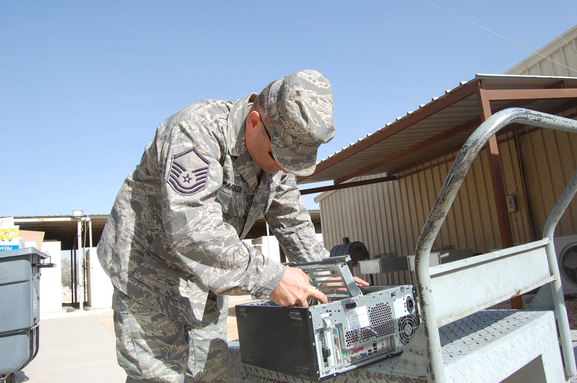 SOUTHWEST ASIA -- Master Sgt. Larry Parker, 64th Expeditionary Support Squadron Communication Flight, repairs and cleans computer hardware outside a dining facility at an undisclosed location Dec. 9. Sergeant Parker, a deployed member from Duke Field's  919th Special Operations WIng, recently updated his unit with more than 70 new computers in support of the mission.  (U.S. Air Force photo/Staff Sgt. Kyle Ray)
