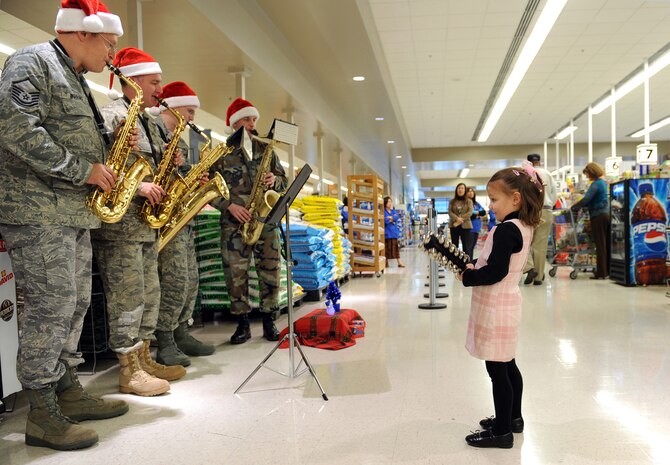 NELLIS AIR FORCE BASE, Nev. - A young commissary patron accompanies the United States Air Force Band of the Golden West by playing bells on Dec. 14.  The four piece saxophone quartet from Travis Air Force Base comprised of Master Sgt. Jim Boubonis, Tech. Sgt. Jim Butler, Senior Airman Ron Glenn and Master Sgt. Tony Seres visited various location throughout the installation to play traditional Christmas songs.  (U.S. Air Force photo/Lawrence Crespo)