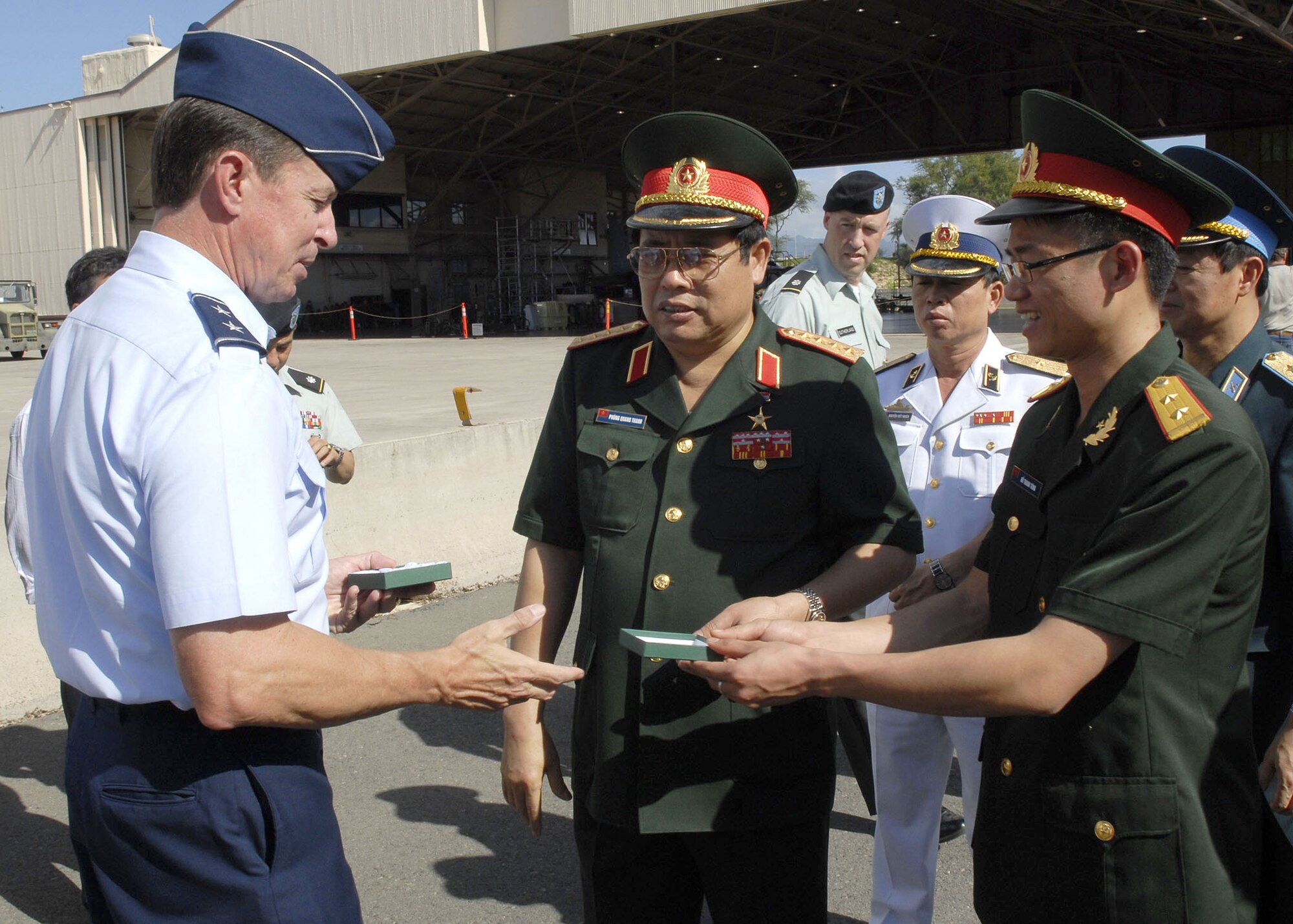 Vietnamese, Minister of Defense, Gen. Phung Quang Thanh, and Lt. Do Thanh Thung, Assitant, Department of Foreign Affairs Relations, offer a gift to  Maj. Gen David L. Commons, Mobilization Assistant, to the Pacific Air Forces, commander, during a tour of Hickam Air Force Base, Hawaii on Dec. 11 . (U.S. Air Force photo/Tech. Sgt. Jerome S. Tayborn)