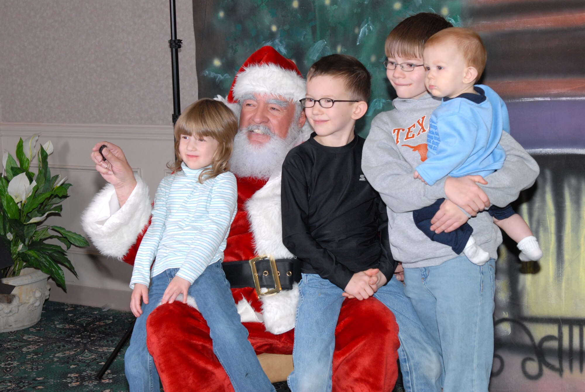 Mae, 4, Brady, 9, Preston, 7, and Trent, 10 months, all children of Master Sgt. Greg Armstrong, a 154th Training Squadron flight engineer,  have their photo taken with Santa Claus Dec. 15 for the holidays. The Airman Family Readiness Center coordinated the photo session with Santa, gifts by Cathedral Saint Andrew and teddy bears and cookies from Pinnacle Pointe. (U.S. Air Force Photo by Senior Airman Christine Clark)