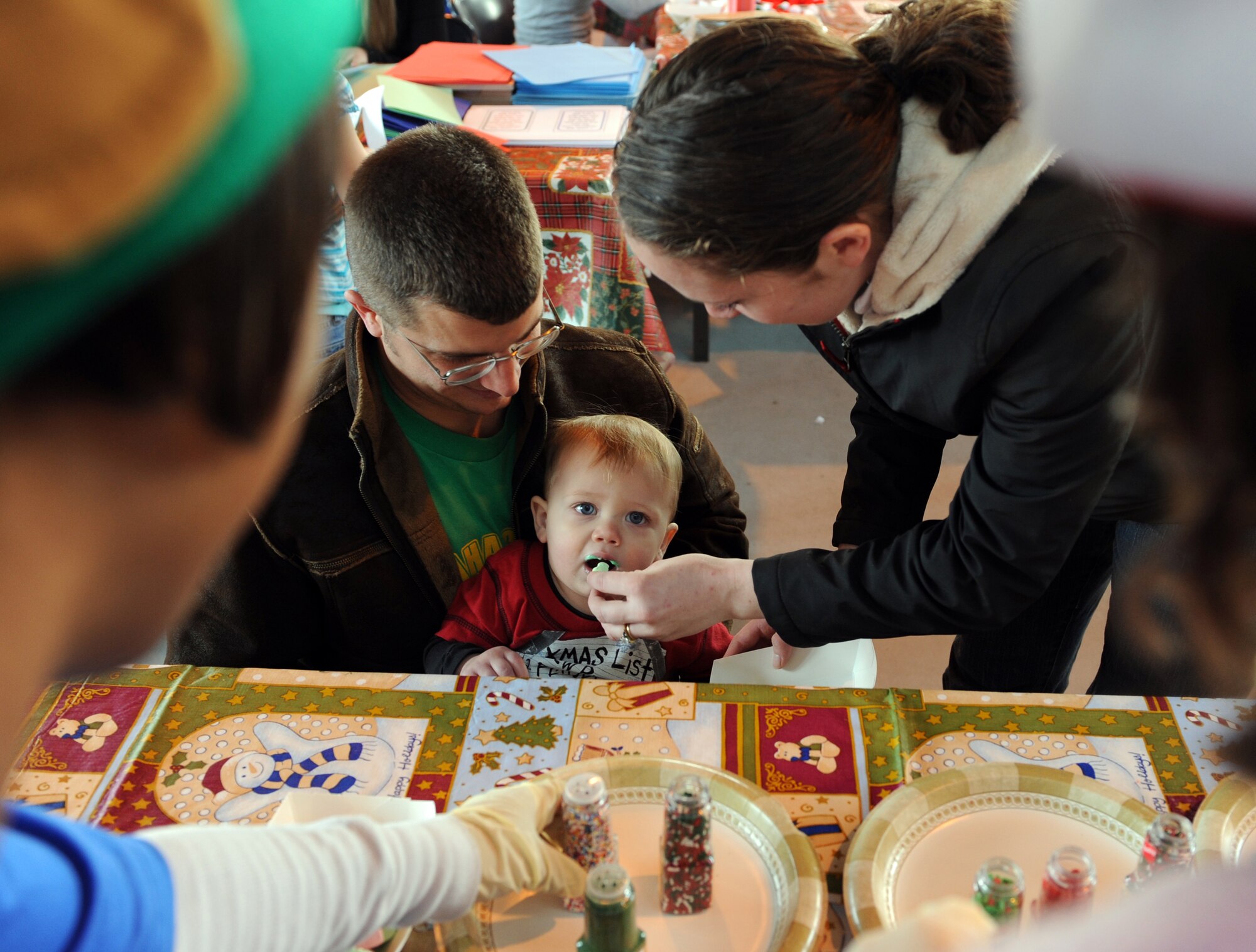MOUNTAIN HOME AIR FORCE BASE, Idaho -- Jim and Maura Harris feed their son Cal, 2, cookies they made as a family during Fun Zone Winter Wonderland Dec. 5 in hangar 201. There were bouncy castles, carnival games, prizes, carnival rides and a special visit from Santa Claus. For more information on  366th Force Support Squadron events visit www.mhafb-fun.com. (U.S. Air Force photo by Airman 1st Class Debbie Lockhart)