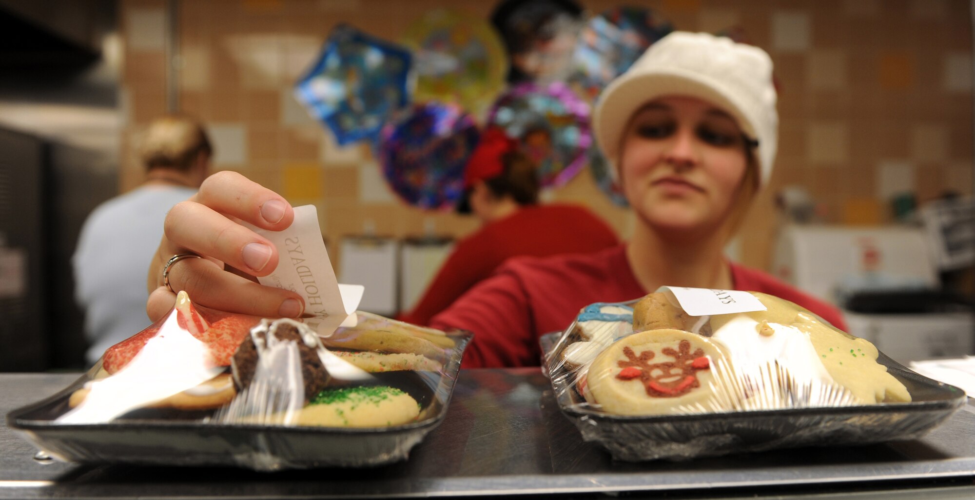 MOUNTAIN HOME AIR FORCE BASE, Idaho -- Stephanie Higgins places stickers on packaged cookies during the annual cookie drive at the commissary Dec. 7. The 366th Fighter Wing's Annual Holiday Cookie Drive takes place during the first part of December to provide the base’s dorm residents a comforting taste of home in the form of a dozen cookies. (U.S. Air Force photo by Airman 1st Class Debbie Lockhart)